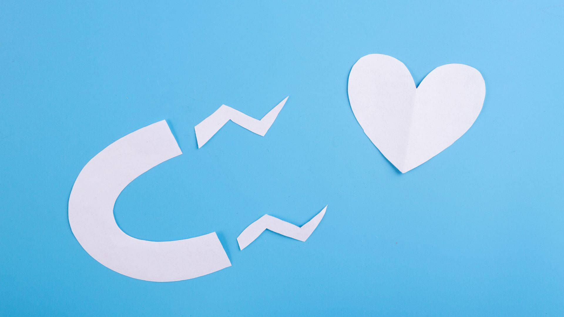 愛心 桌布 壁紙 — 一個破損的白色紙磁鐵和心形圖案放置在純藍色背景上。