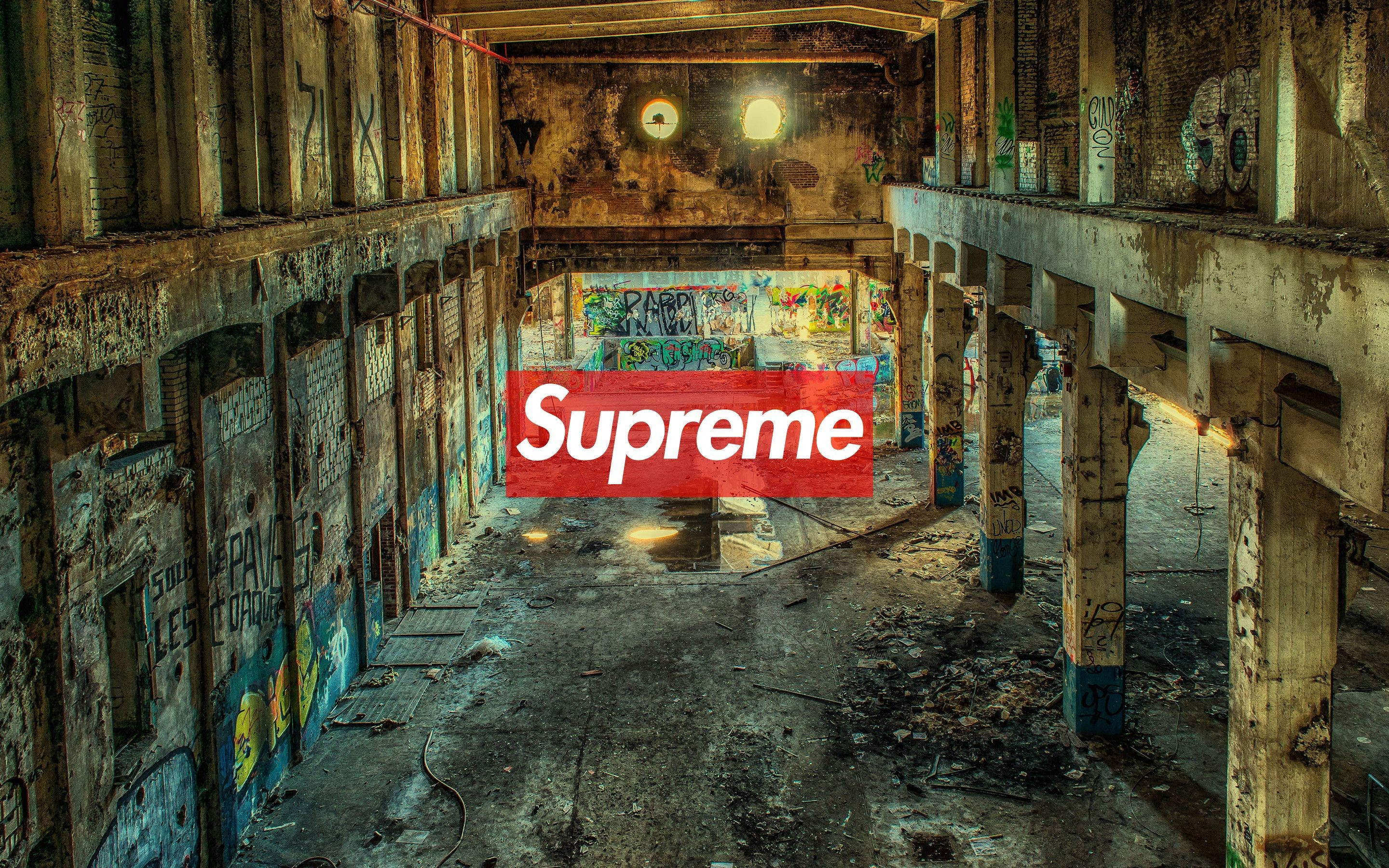 supreme 桌布 壁紙 — 一個破舊的工業內部，牆上佈滿塗鴉，前景中央有一個紅色的Supreme標誌。