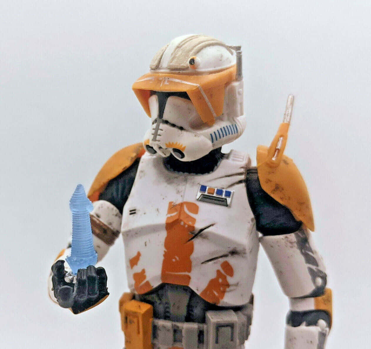 The Order 66 桌布 壁紙 — 一個破舊的星際大戰複製人突擊隊員動作人偶在純白色背景前拿著一把藍色光劍柄。