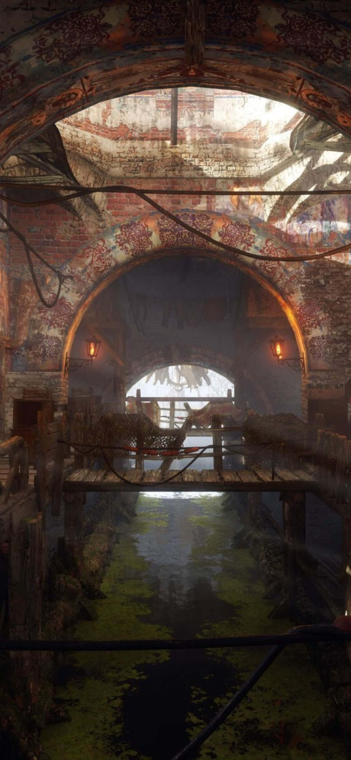 iPhone X Metro Exodus 桌布 壁紙 — 一個破舊的磚拱門框住一條渾濁的水道，水道上長滿藻類，電線懸掛在昏暗的燈光下。