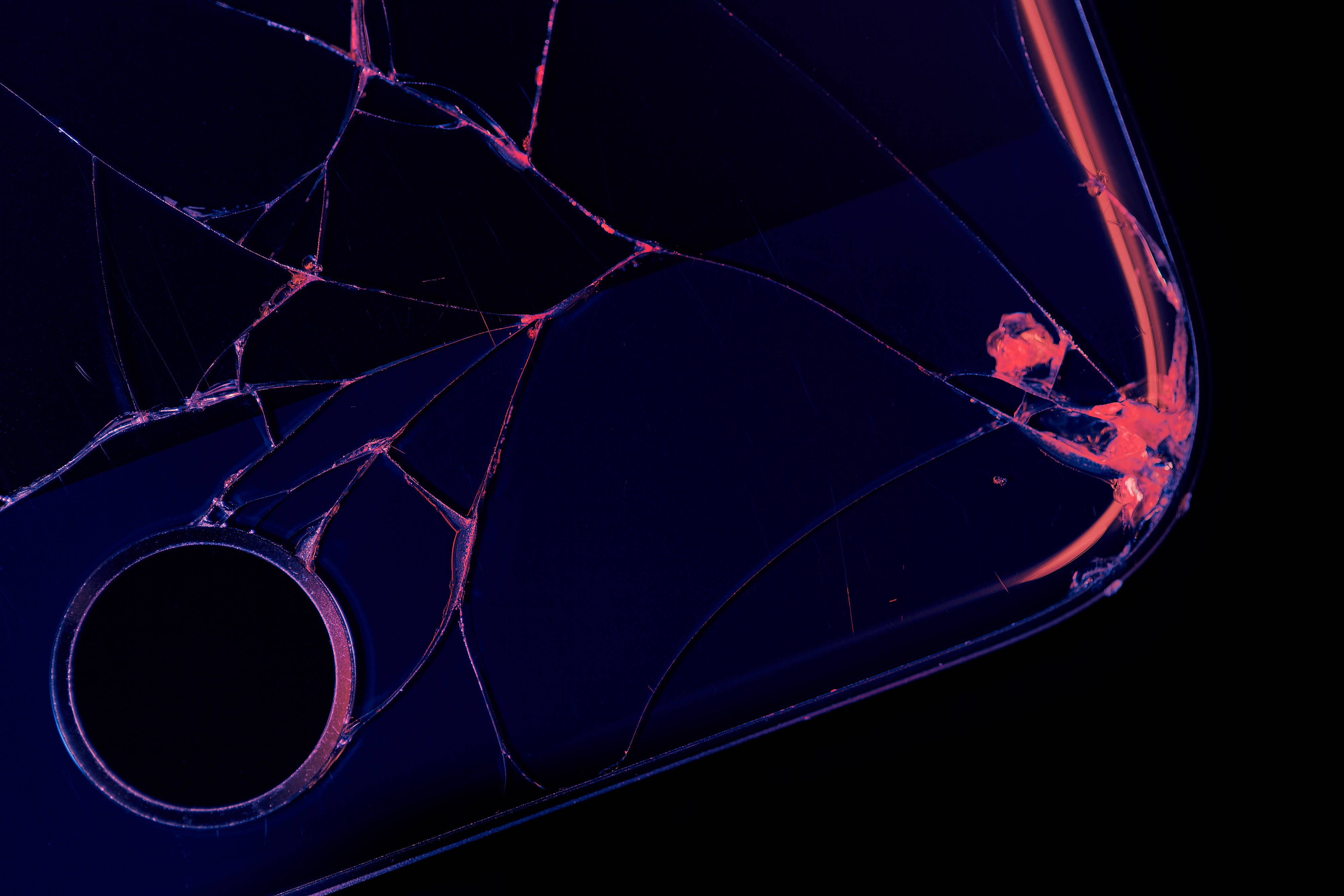 black apple iPhone 桌布 壁紙 — 一個破裂的智慧型手機螢幕在黑色背景上發出霓虹粉紅和藍色光芒。