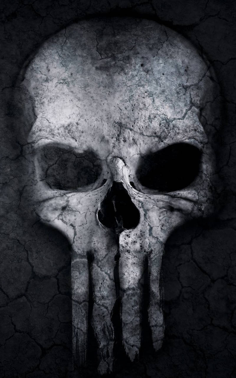 Punisher Skull 桌布 壁紙 — 一個破裂的頭骨，下顎線刻有懲罰者標誌，從黑暗破裂的混凝土背景中浮現。
