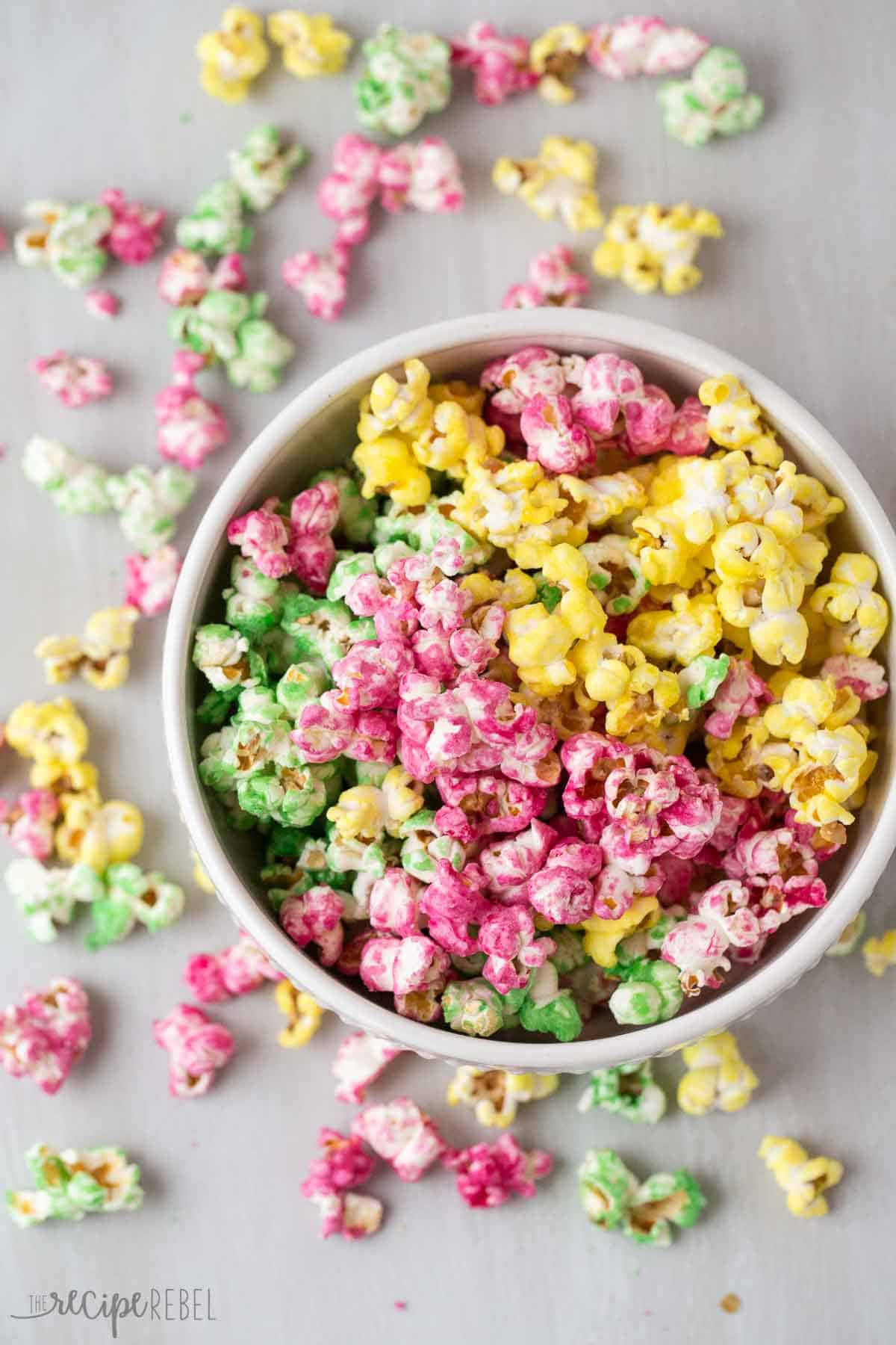 Popcorn 桌布 壁紙 — 一個碗裝滿了色彩繽紛的粉紅色、綠色和黃色糖果爆米花，散落在淺灰色表面上。