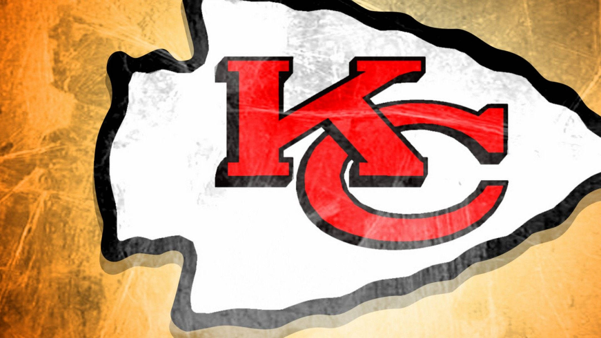 Kc Chiefs 桌布 壁紙 — 一個磨損的堪薩斯城酋長隊標誌，以紅色和白色呈現，背景為有紋理的金色。