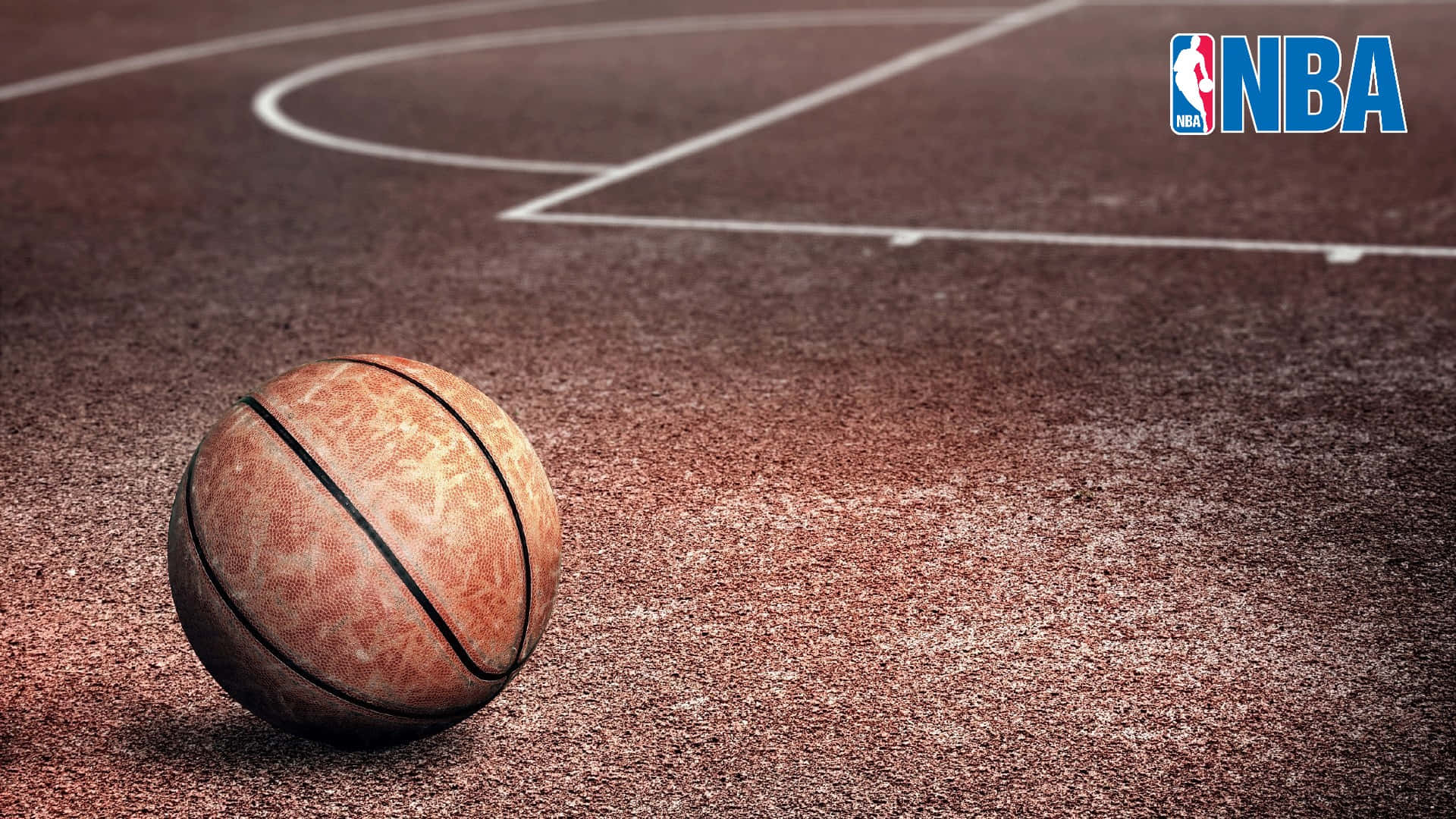 1080p Basketball 桌布 壁紙 — 一個磨損的籃球放在有紋理的球場上，球場有白線和角落的NBA標誌。