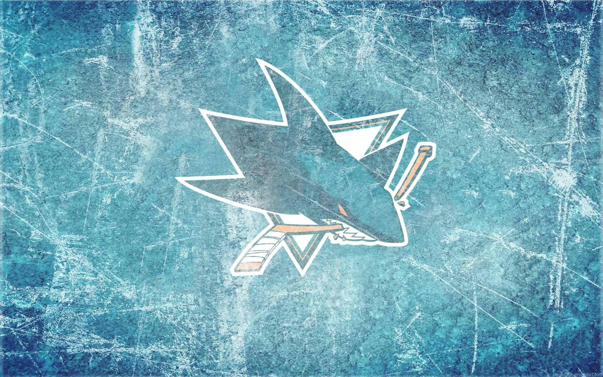sharks 桌布 壁紙 — 一個磨損的藍色溜冰場背景，上面有一個風格化的鯊魚標誌，手持曲棍球棒，表面有白色刮痕。