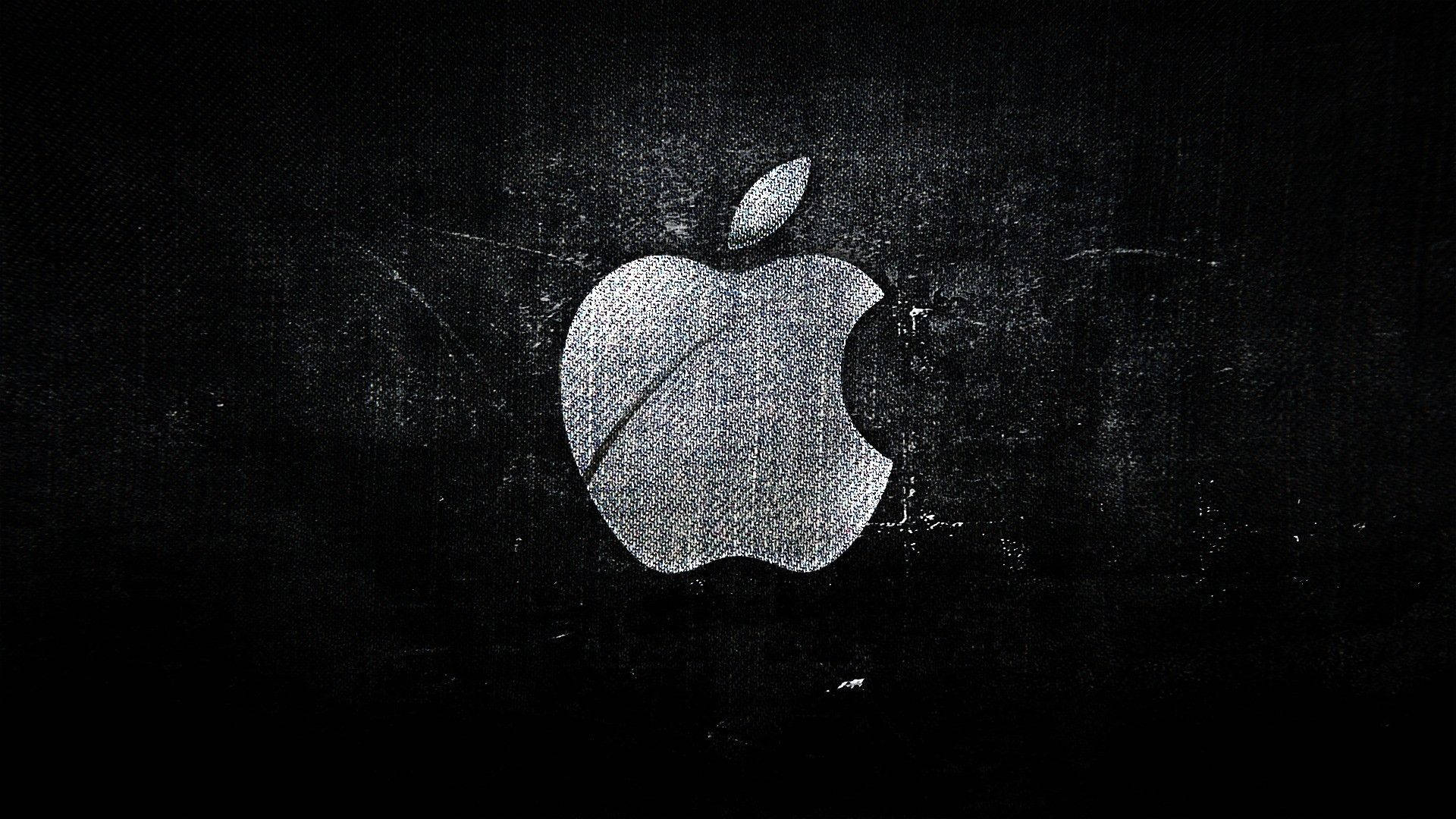 MacBook 動態圖片 桌布 壁紙 — 一個磨損的銀色Apple標誌在帶有刮痕和顆粒的紋理黑色背景上發光。