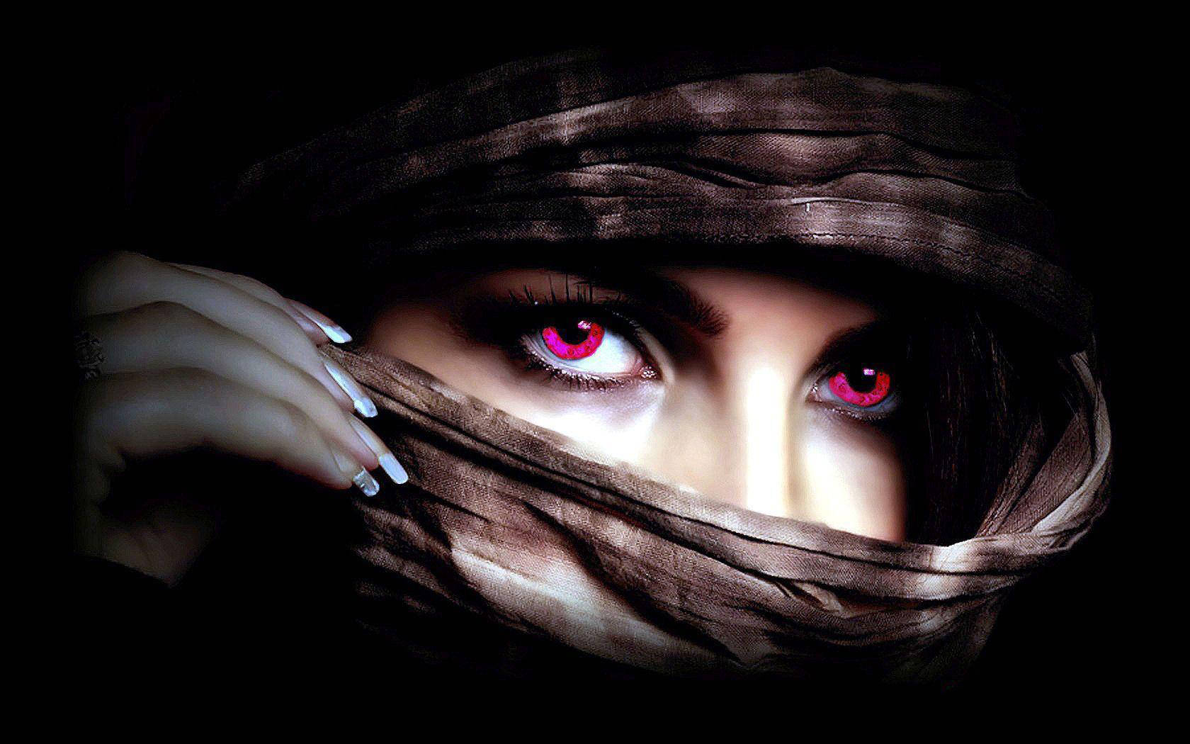 Eyes 桌布 壁紙 — 一個神秘人物，眼睛發出紅光，透過深棕色面紗窺視，背景為黑色。