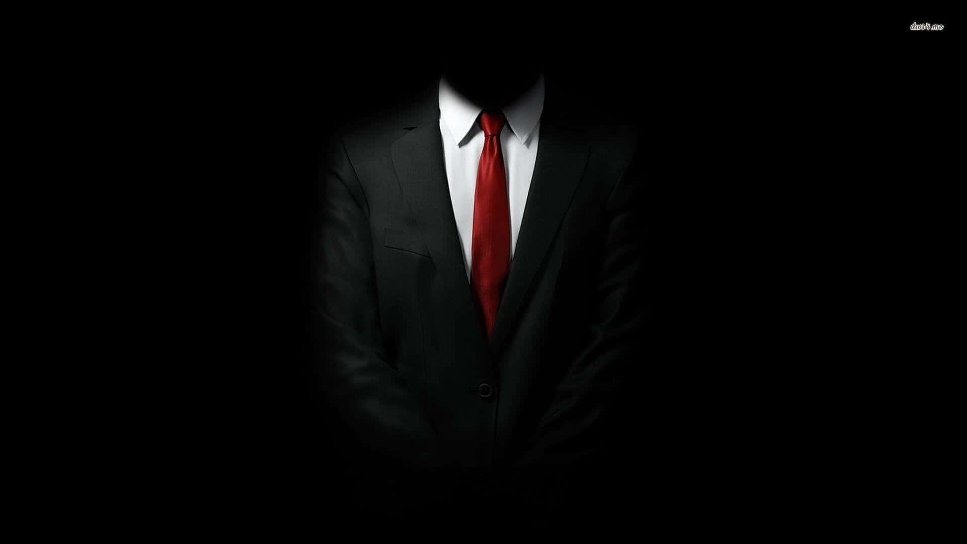 suit 桌布 壁紙 — 一個神秘人物身穿黑色西裝和紅色領帶，站在黑暗中，沒有可見的臉。