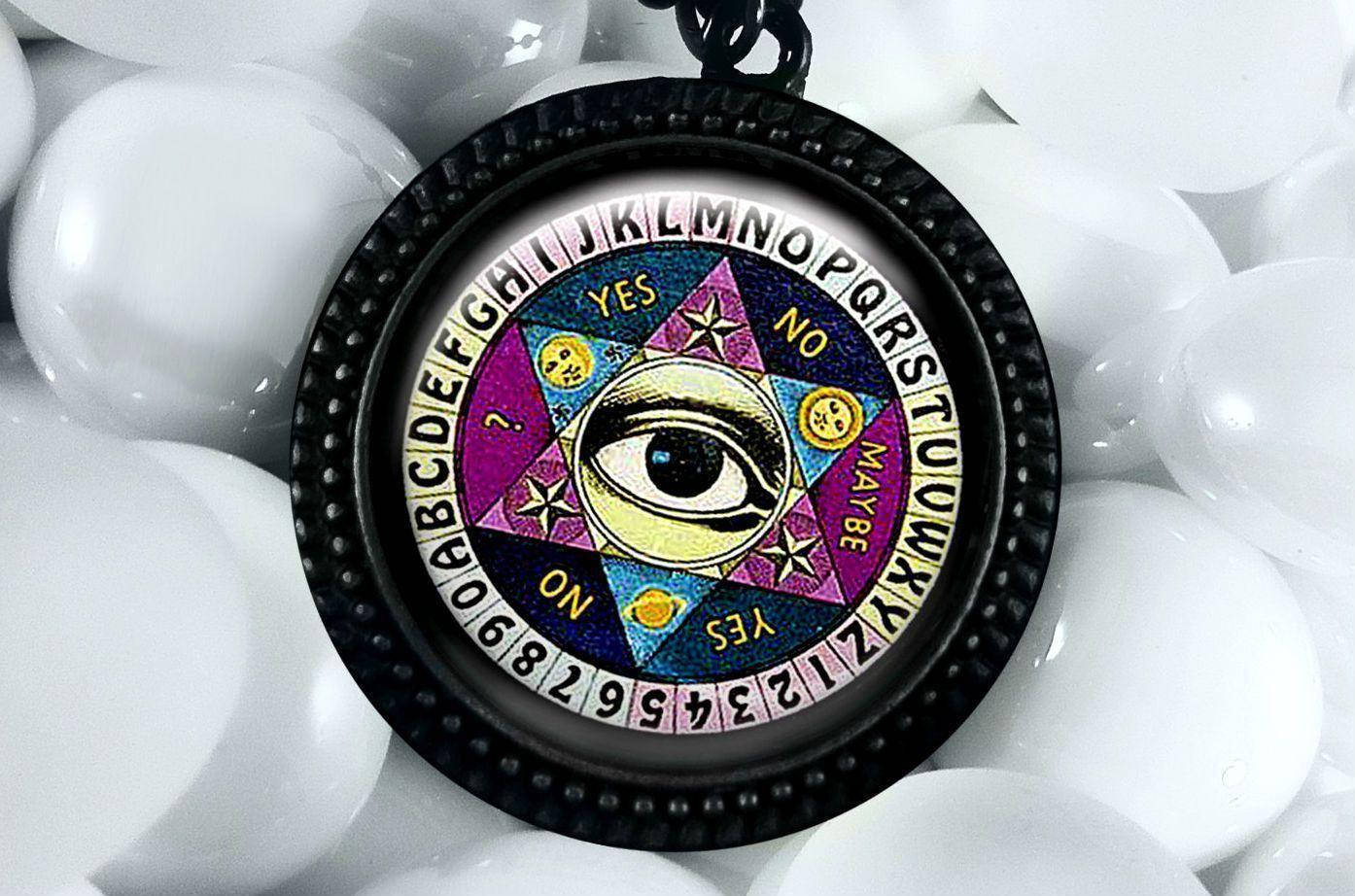 witchcraft 桌布 壁紙 — 一個神秘的占卜板吊墜，帶有全視之眼和字母環，安放在白色彈珠上。