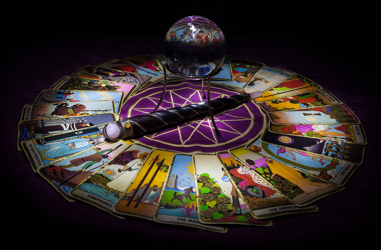 Tarot Card 桌布 壁紙 — 一個神秘的塔羅牌閱讀設置，水晶球和華麗的魔杖位於紫色五角星中央，周圍散落著牌。