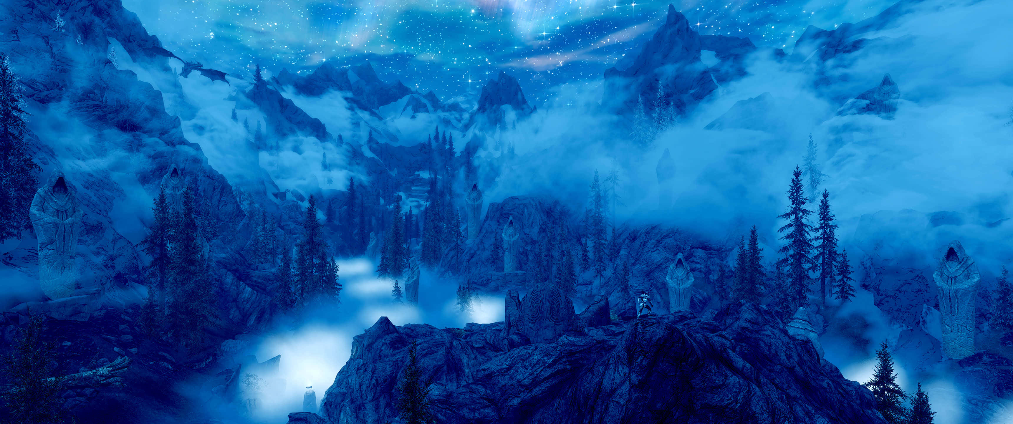 3440x1440p The Elder Scrolls V Skyrim 桌布 壁紙 — 一個神秘的山谷沐浴在空靈的藍光中，發光的廢墟從霧氣中浮現，上方是繁星點點的夜空。