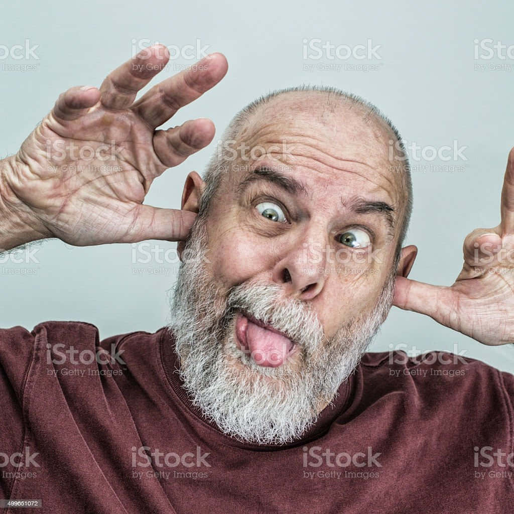 meme 桌布 壁紙 — 一個禿頭灰鬍鬚的男人做出一個愚蠢的表情，伸出舌頭並用雙手捂住耳朵。