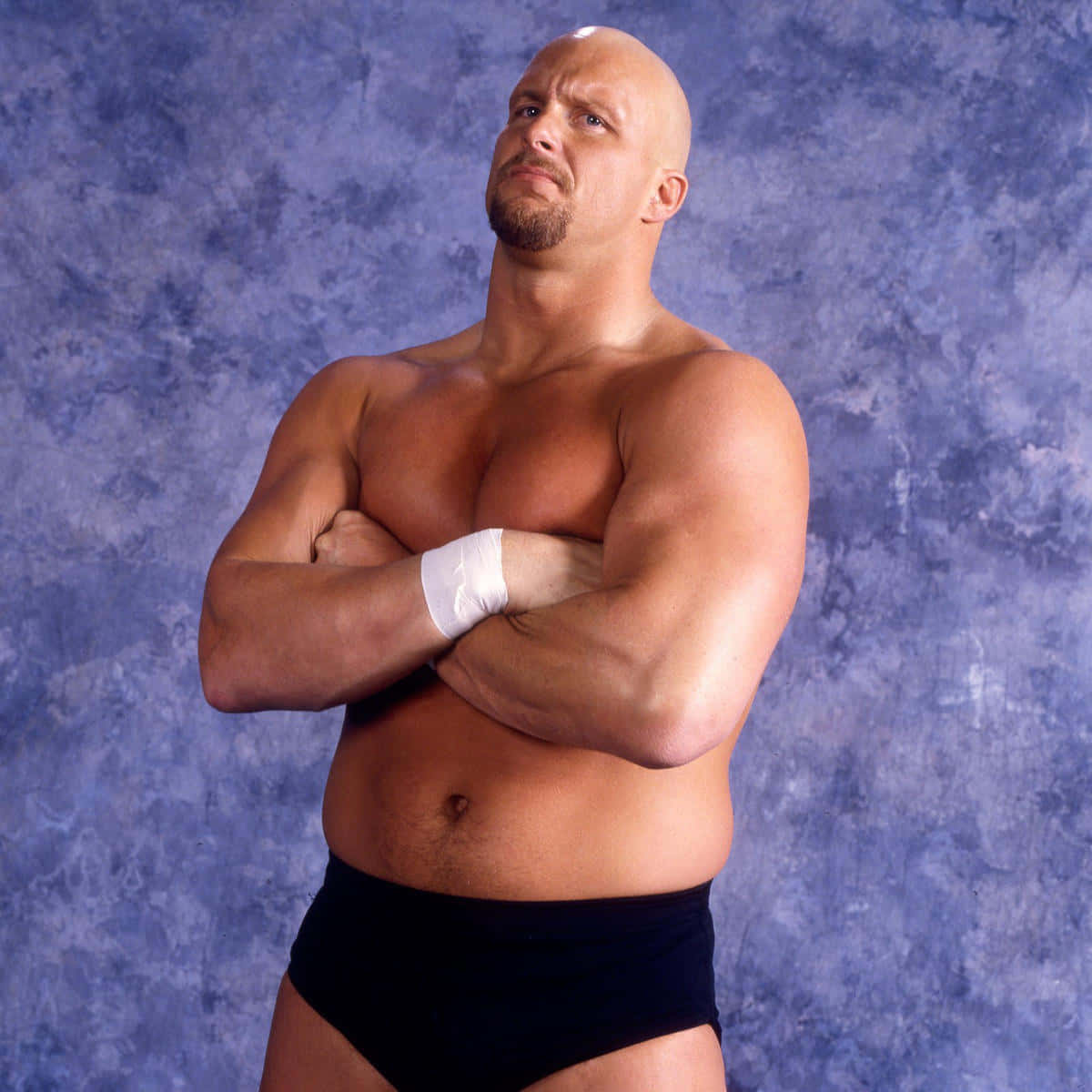 WWE 桌布 壁紙 — 一個禿頭肌肉發達、留著山羊鬍的摔角手自信地交叉雙臂，站在有紋理的藍色背景前。
