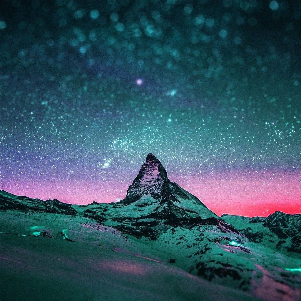 iPad 桌布 壁紙 — 一個積雪的山峰在充滿活力的星空下升起，青綠色和粉紅色的極光在山峰上發光。