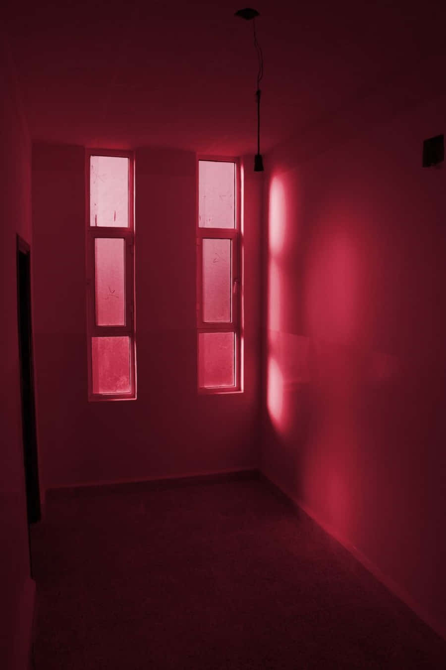 Aesthetic Dark Pink 桌布 壁紙 — 一個空房間，被兩扇高窗透進的詭異紅光照亮，在樸素的牆壁上投下長長的影子。