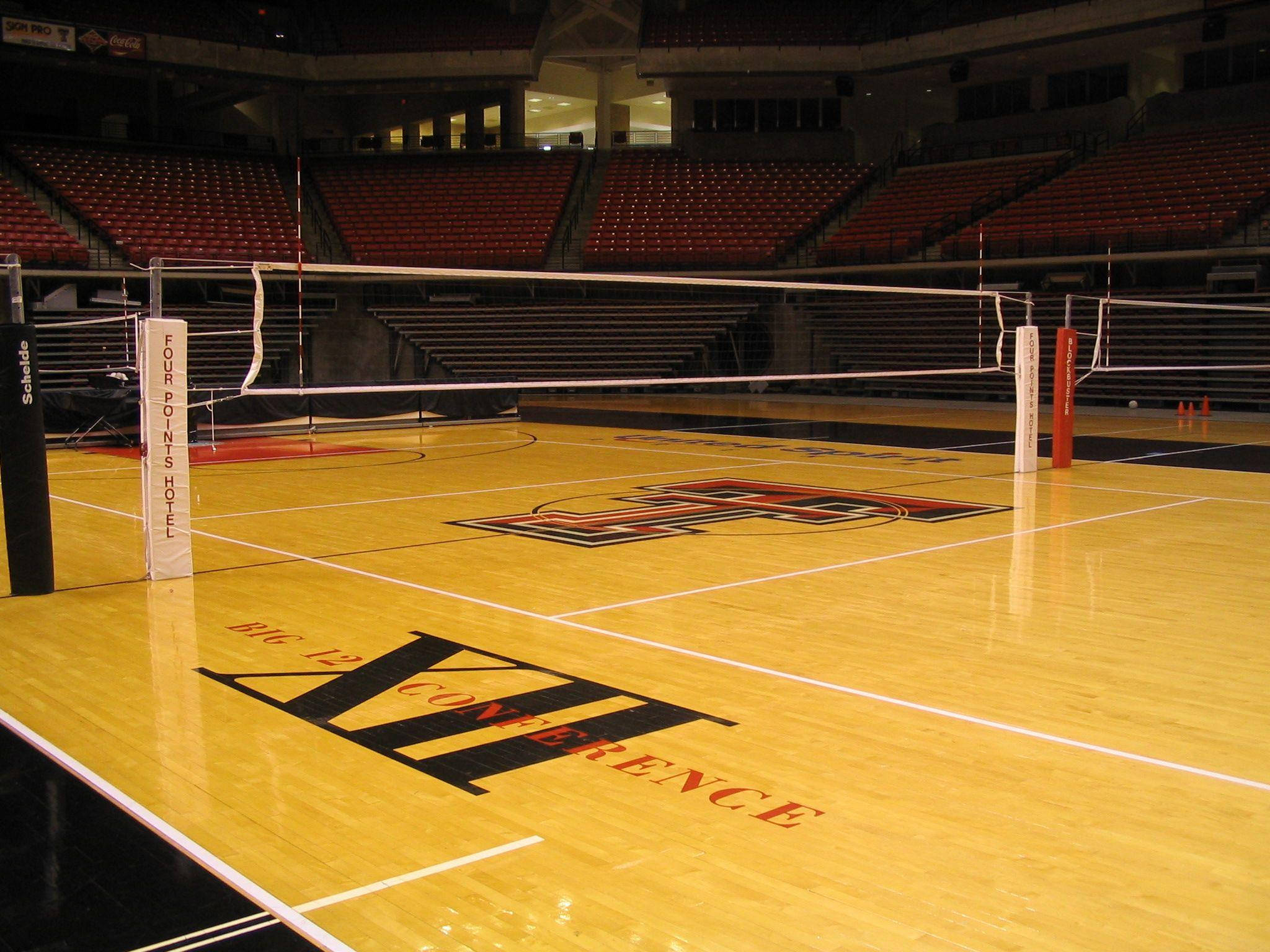 volleyball 4K 桌布 壁紙 — 一個空曠的室內排球場，拋光木地板和紅色座位，在明亮的燈光下。