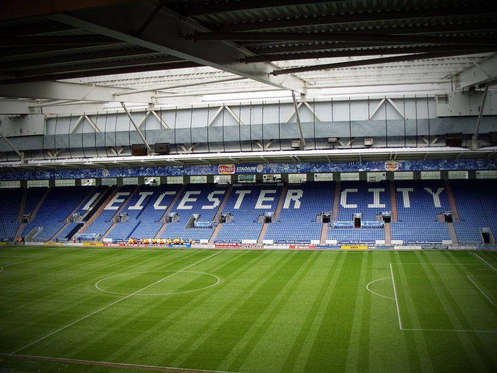 足球 桌布 壁紙 — 一個空無一人的足球場，藍色座位拼出「LEICESTER CITY」，俯瞰著充滿活力的綠色球場。