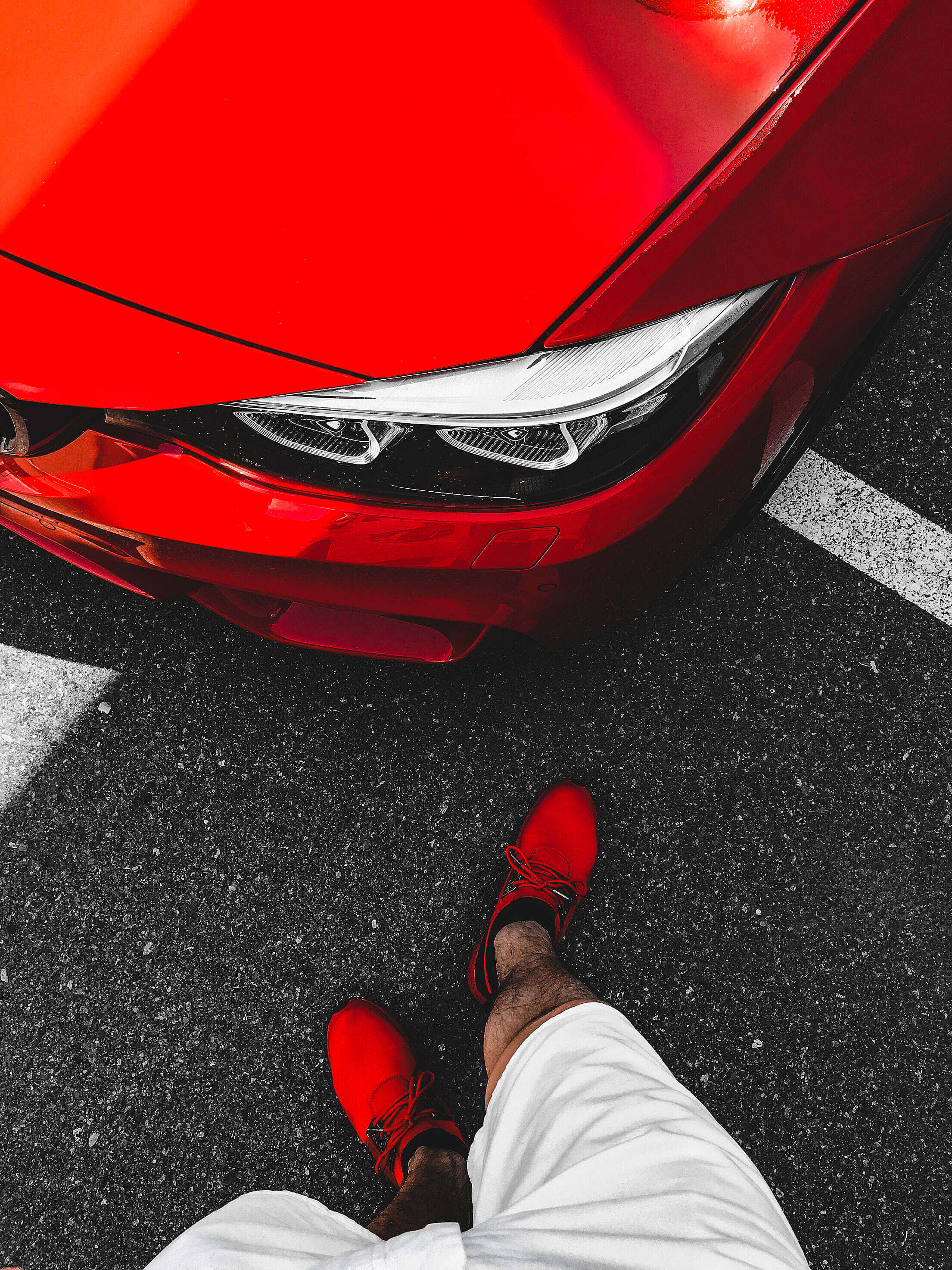 Red Shoes 桌布 壁紙 — 一個穿紅鞋的人站在有白色停車線的瀝青路上，旁邊是一輛亮紅色的汽車。