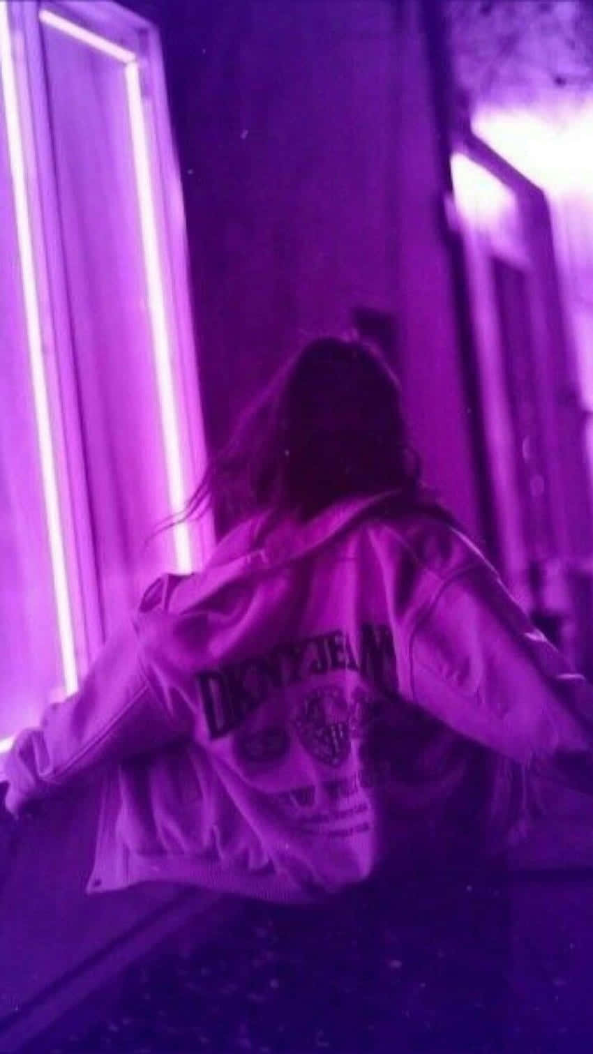 Violet Aesthetic 桌布 壁紙 — 一個穿著DKNY外套的人背對鏡頭，站在夜晚紫色霓虹燈照亮的巷子裡。