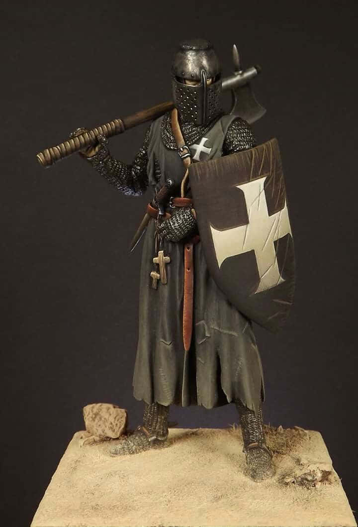 Crusader 桌布 壁紙 — 一個穿著全套盔甲的詳細騎士人偶，手持帶有白色十字架的戰斧和盾牌，站在沙質底座上。