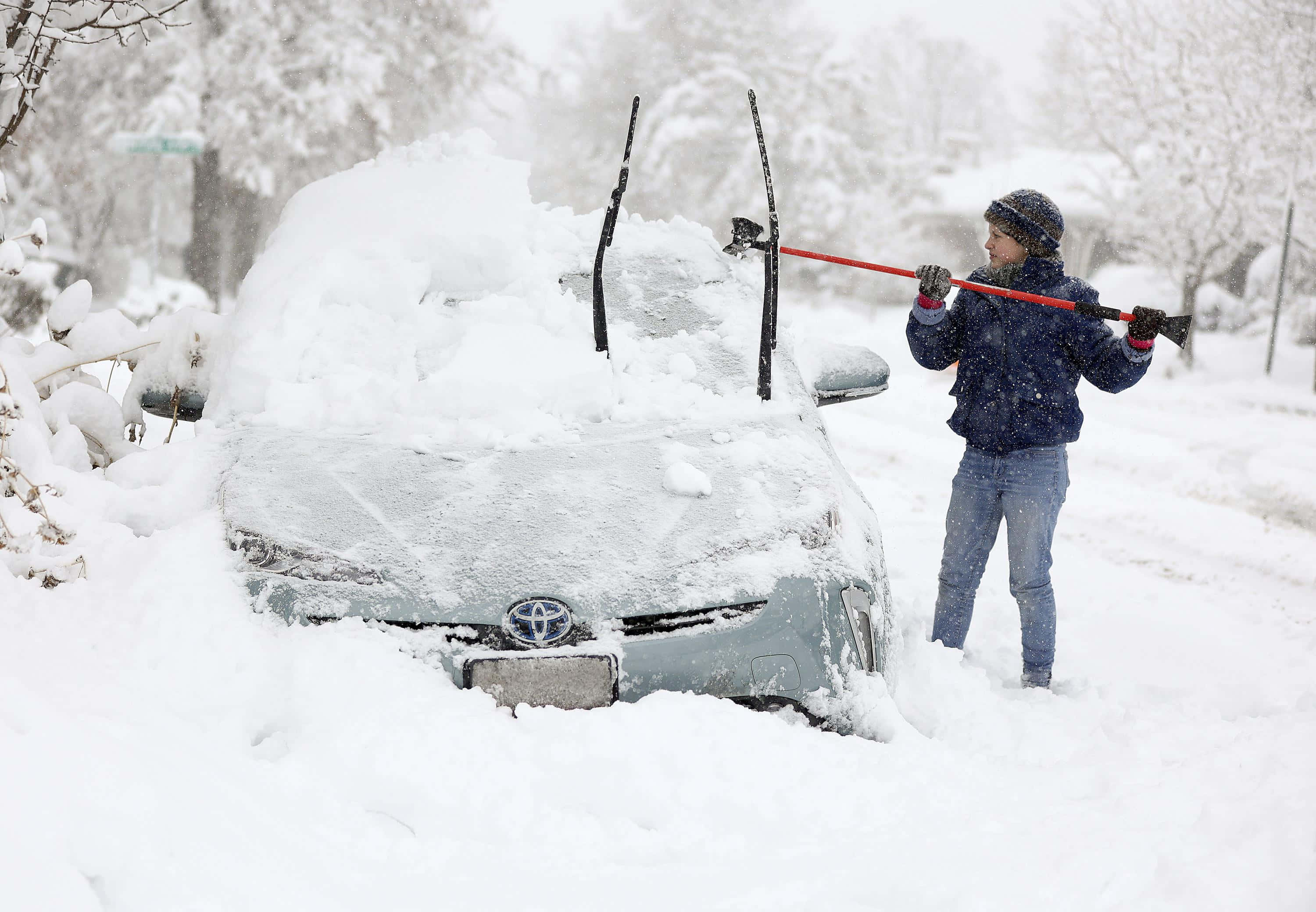 Winter 桌布 壁紙 — 一個穿著冬季裝備的人正在暴風雪中清除被厚厚白雪覆蓋的汽車上的積雪。
