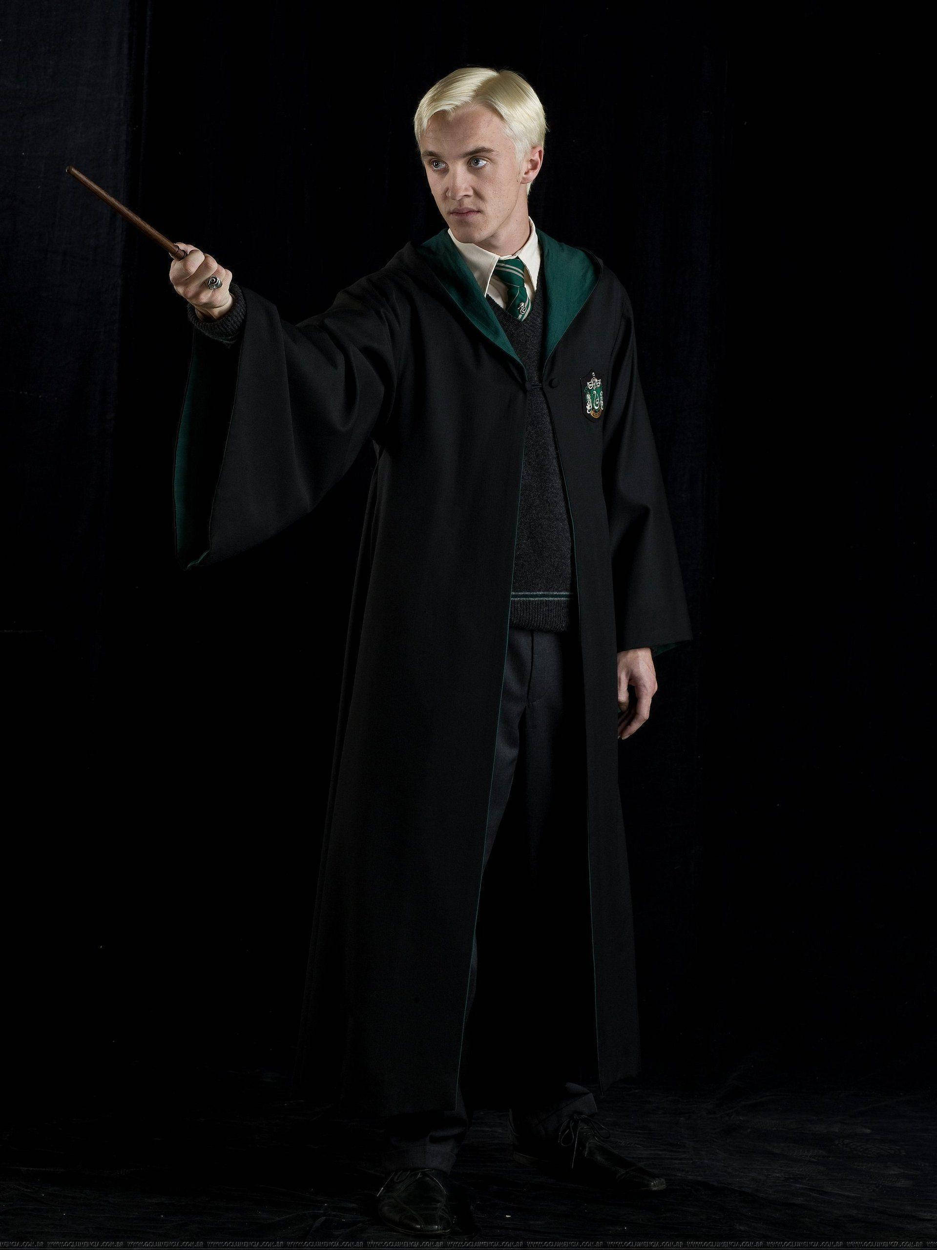 draco 桌布 壁紙 — 一個穿著史萊哲林長袍的年輕男子，在黑暗背景下將魔杖指向前方。