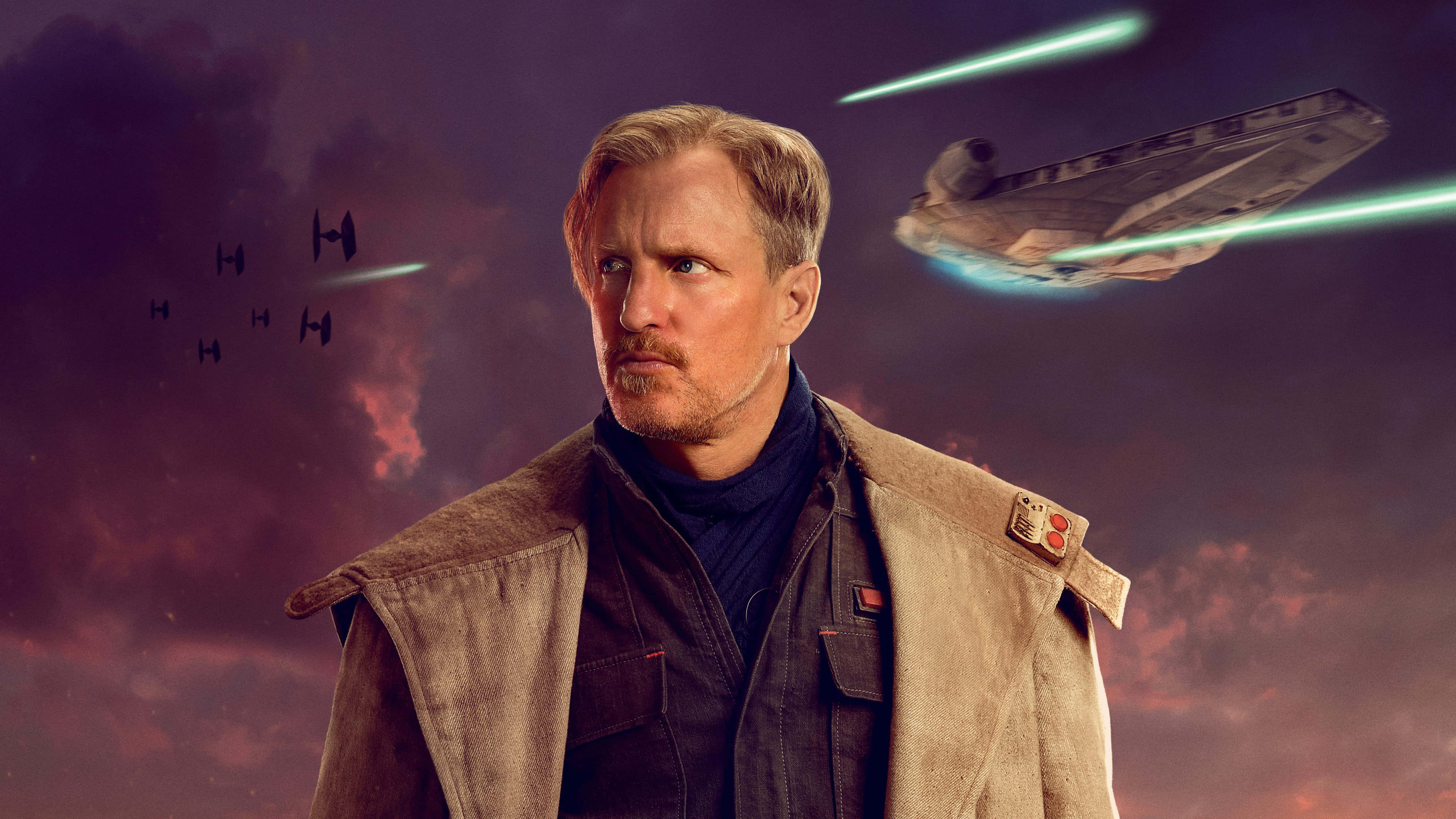 Solo A Star Wars Story 桌布 壁紙 — 一個穿著堅固背心的男人站在戲劇性的天空下，星際戰鬥機和千年鷹號在發光的激光火線中飛馳而過。