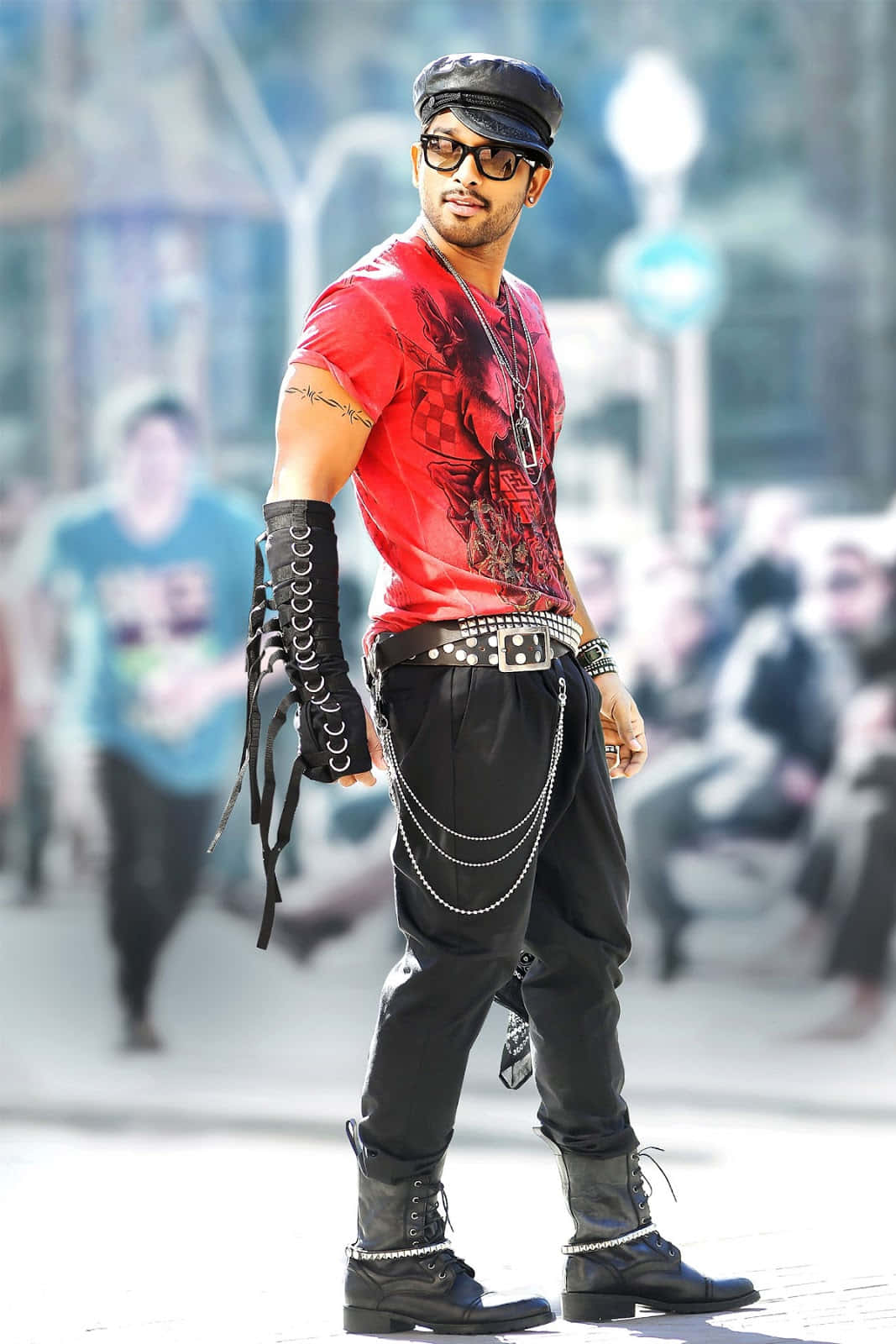 Allu Arjun 桌布 壁紙 — 一個穿著大膽紅色圖案T恤和黑色皮革裝備的男人自信地站在陽光明媚的城市人行道上。