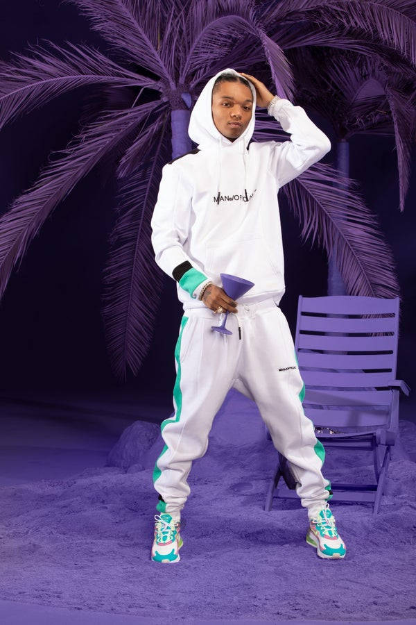 Swae Lee 桌布 壁紙 — 一個穿著帶有青綠色點綴的白色運動服的人，在紫色棕櫚樹下自信地拿著紫色雞尾酒擺姿勢。