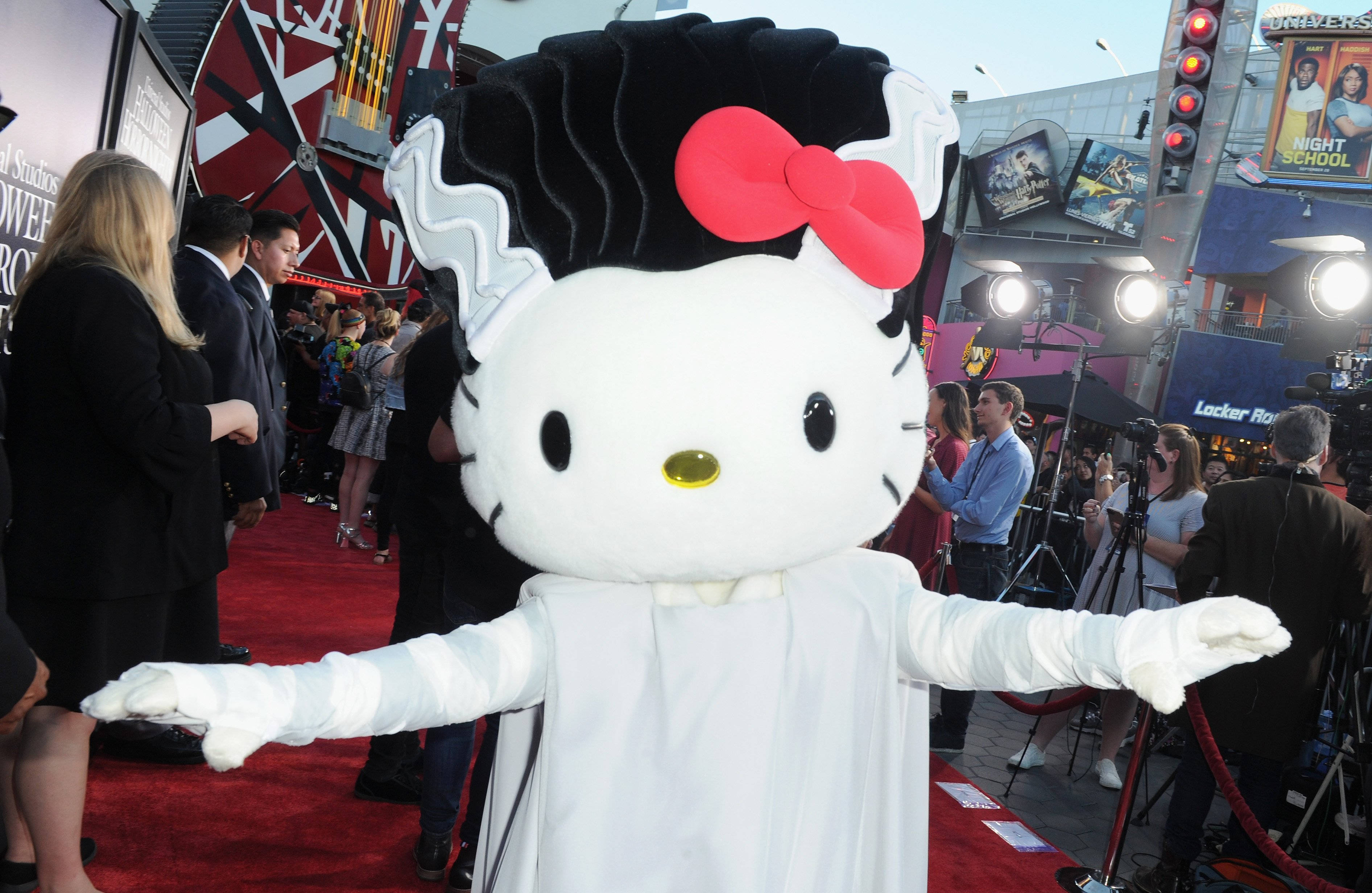 Hello Kitty Halloween 桌布 壁紙 — 一個穿著新娘裝、黑髮紅蝴蝶結的Hello Kitty吉祥物站在好萊塢活動的紅地毯上。