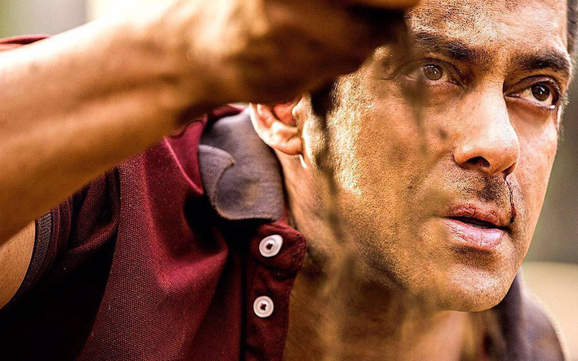 Salman Khan 桌布 壁紙 — 一個穿著栗色襯衫的男人用手遮住眼睛，灰塵在他周圍旋轉，形成粗糙的特寫。