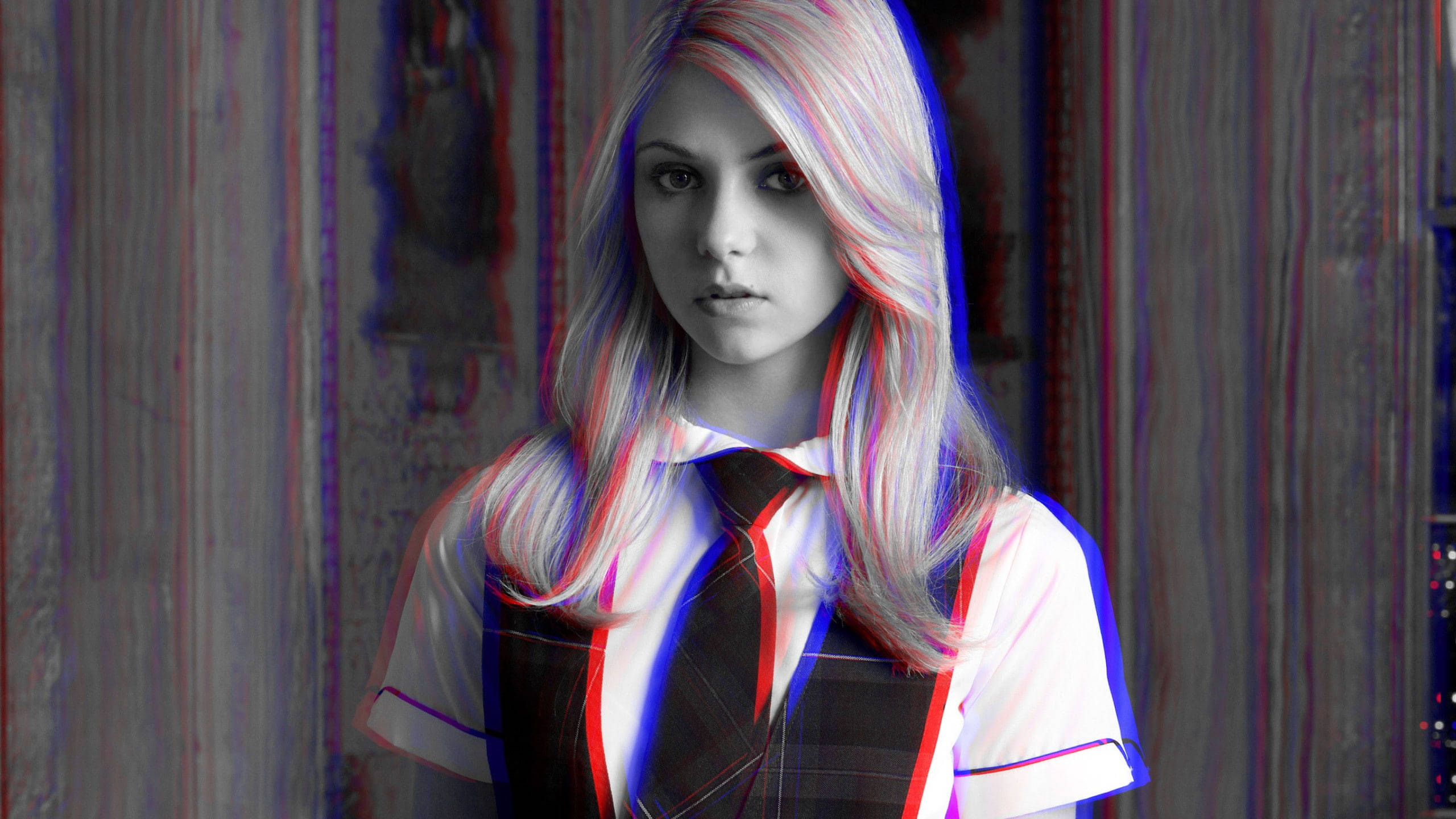Gossip 桌布 壁紙 — 一個穿著校服的女孩，在紋理牆壁前，鮮豔的紅色、藍色和白色故障效果扭曲了她的頭髮和衣服，她凝視著，眼神強烈。