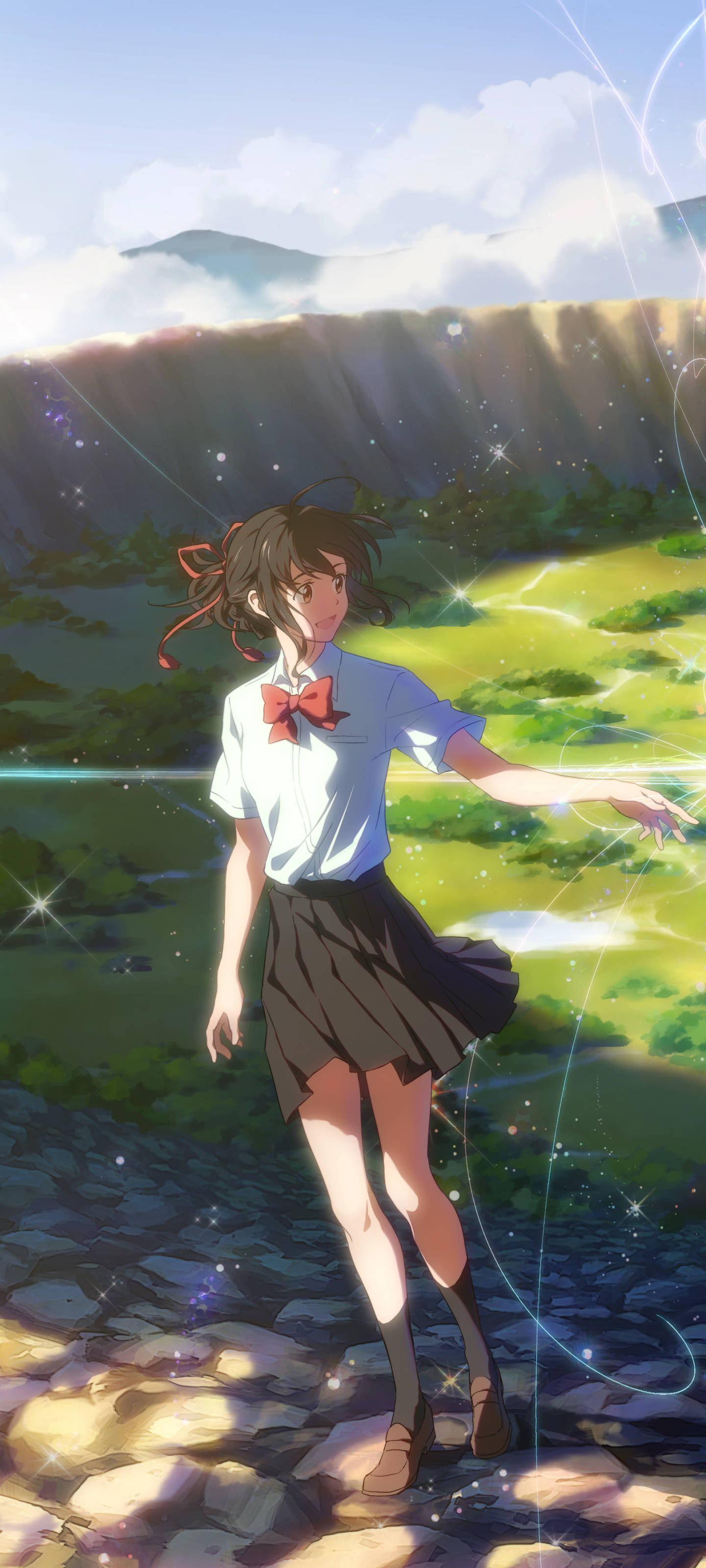 kimi no na wa phone 桌布 壁紙 — 一個穿著校服的年輕動漫女孩站在陽光普照的石徑上，伸出手，發光的魔法粒子在她周圍旋轉，身處一個充滿活力的綠色山谷中。