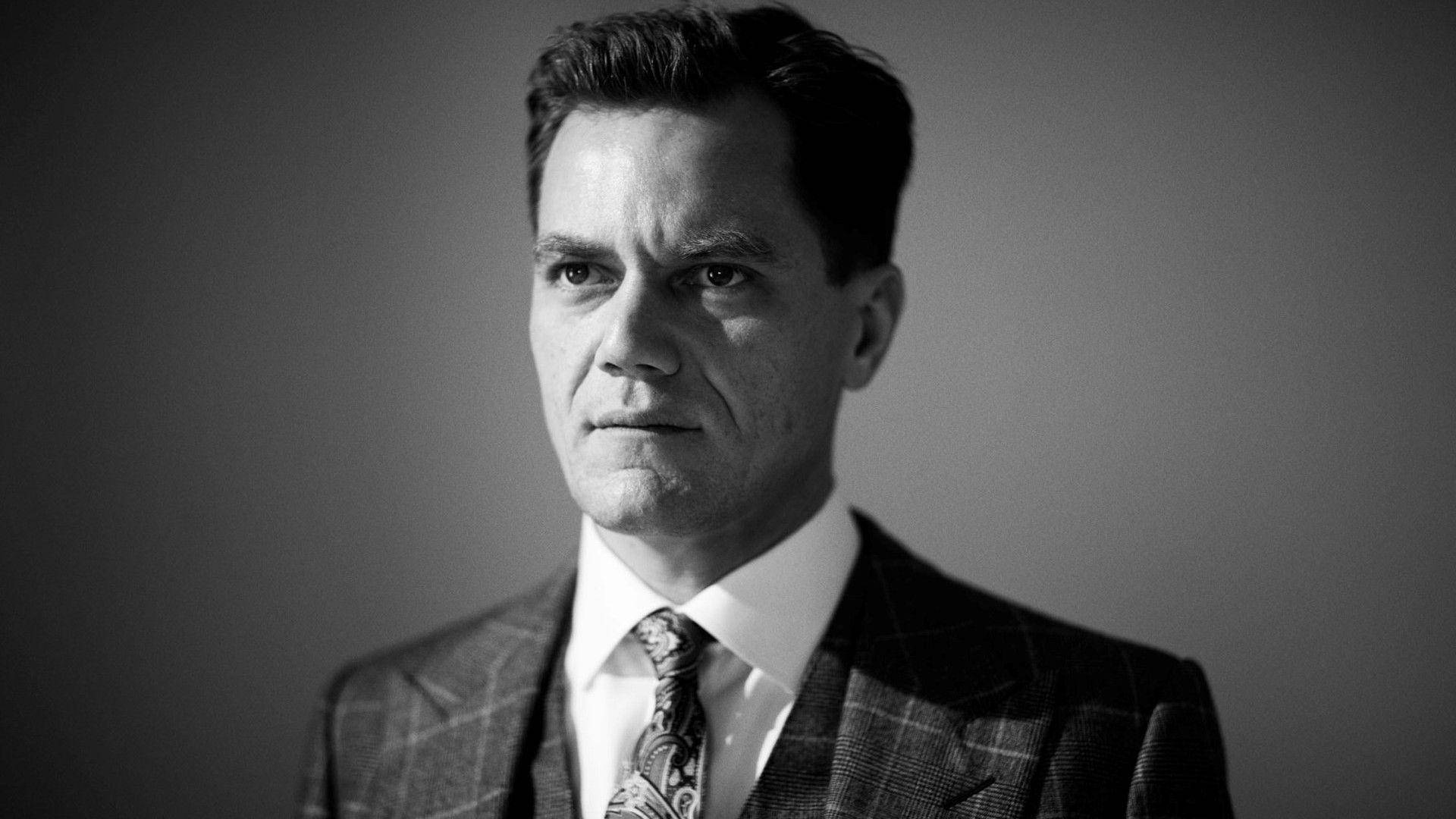Celebrity 桌布 壁紙 — 一個穿著格子西裝和圖案領帶的男人，表情嚴肅，背景簡單的黑白肖像。