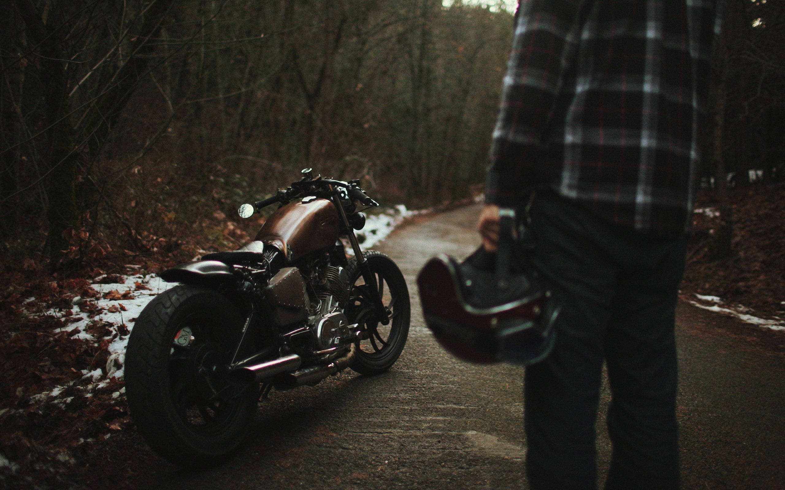 Bobber 桌布 壁紙 — 一個穿著格紋襯衫的人在黃昏時站在一輛訂製摩托車旁，背景是積雪的森林道路。