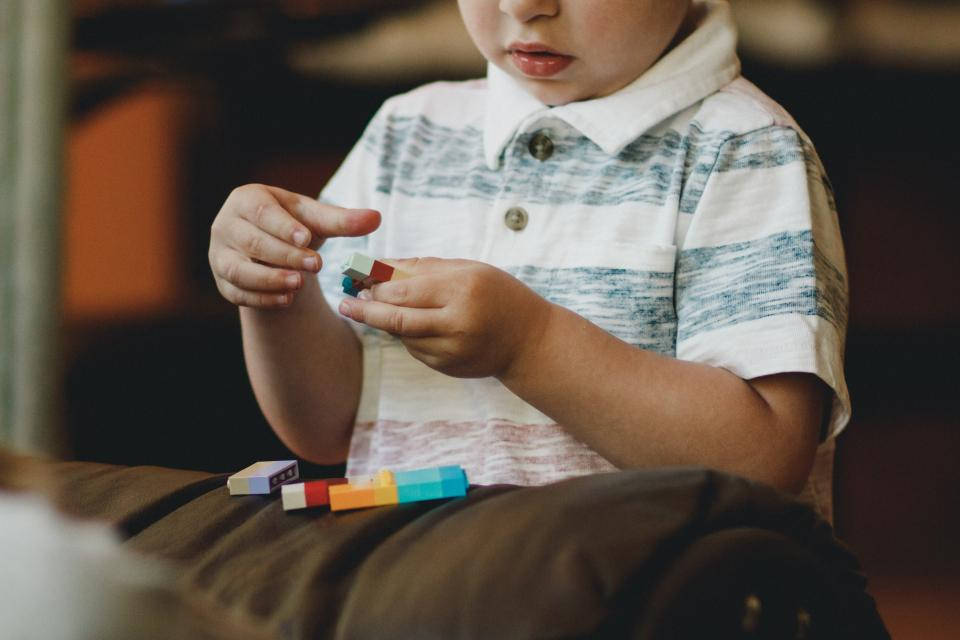 Baby Boy 桌布 壁紙 — 一個穿著條紋衫的小孩正專注地坐在室內組裝色彩繽紛的積木。