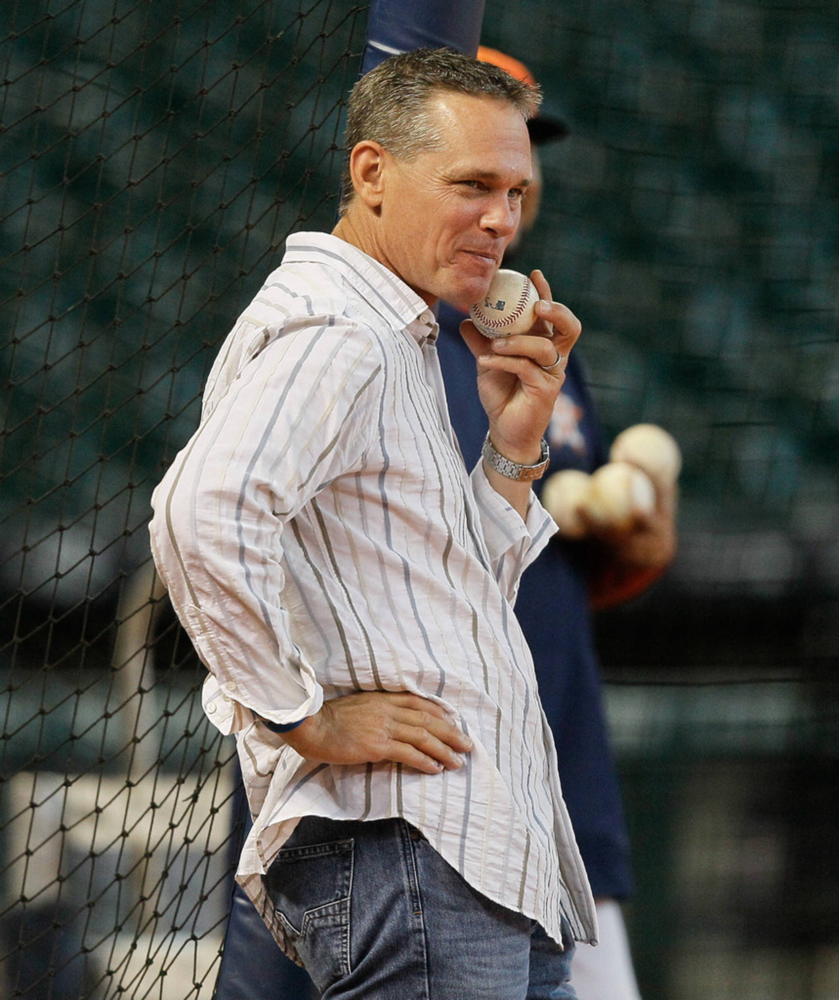 Craig Biggio 桌布 壁紙 — 一個穿著條紋衫的男人站在網牆旁邊，將一個棒球靠近嘴邊。