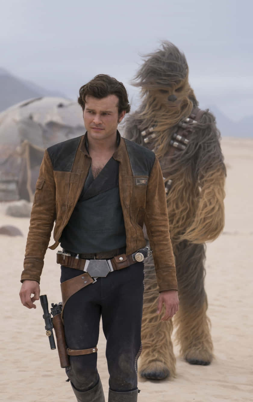 Solo A Star Wars Story 桌布 壁紙 — 一個穿著棕色外套的男人與一個毛茸茸的烏奇並肩走過塵土飛揚的沙漠景觀，天空多雲。