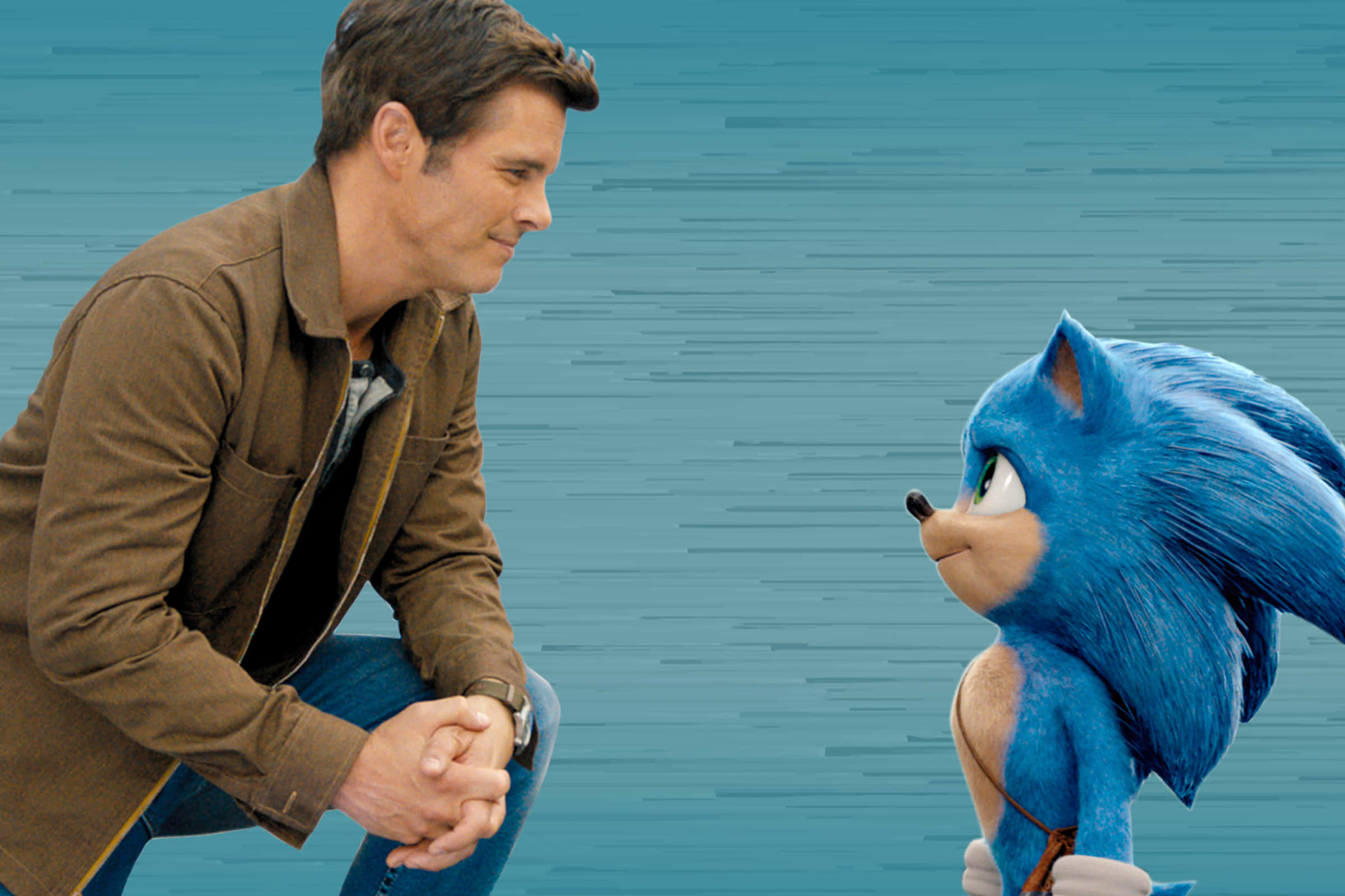 Sonic The Hedgehog 桌布 壁紙 — 一個穿著棕色外套的男人跪下來迎接藍色刺蝟索尼克，場景風格化且充滿電影感。