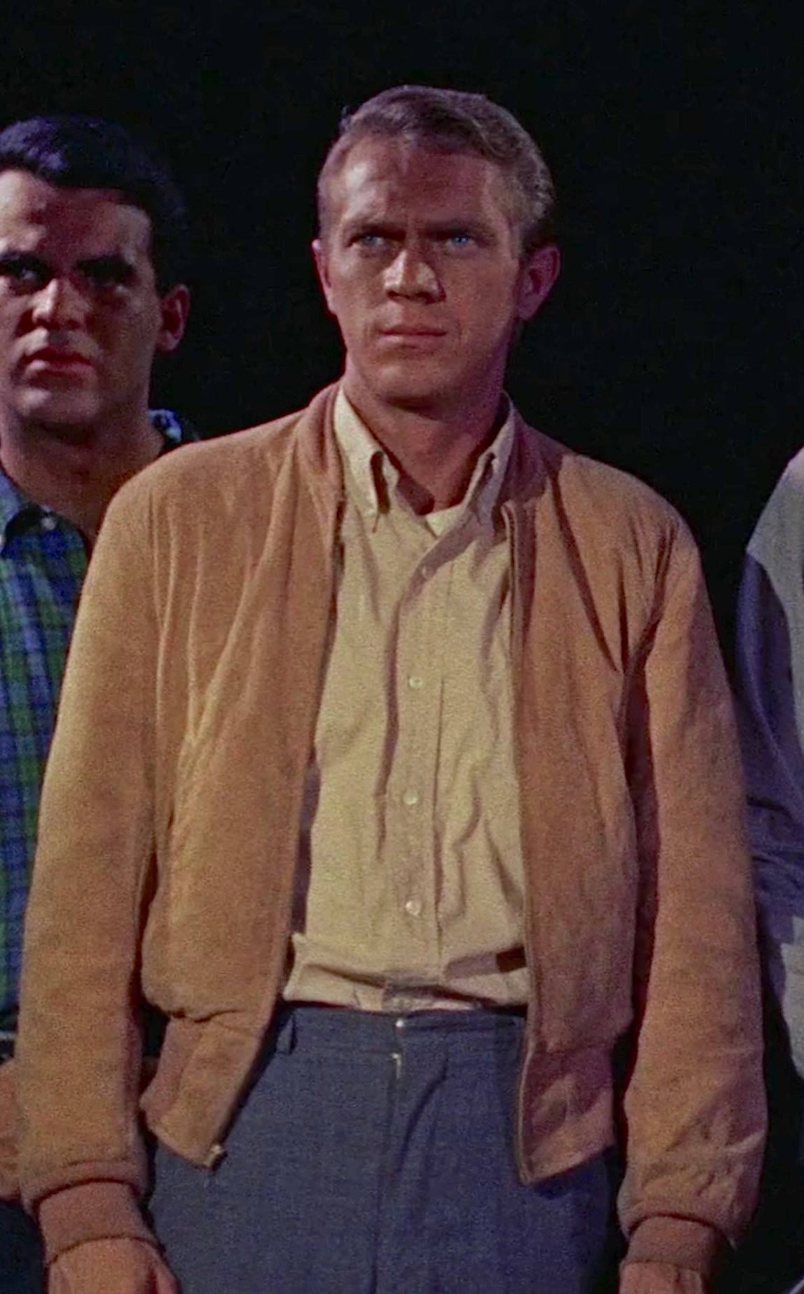 actor 桌布 壁紙 — 一個穿著棕褐色外套和黃色襯衫的男人，在深色背景下帶著嚴肅的表情站立，另一個男人部分可見在他身後。