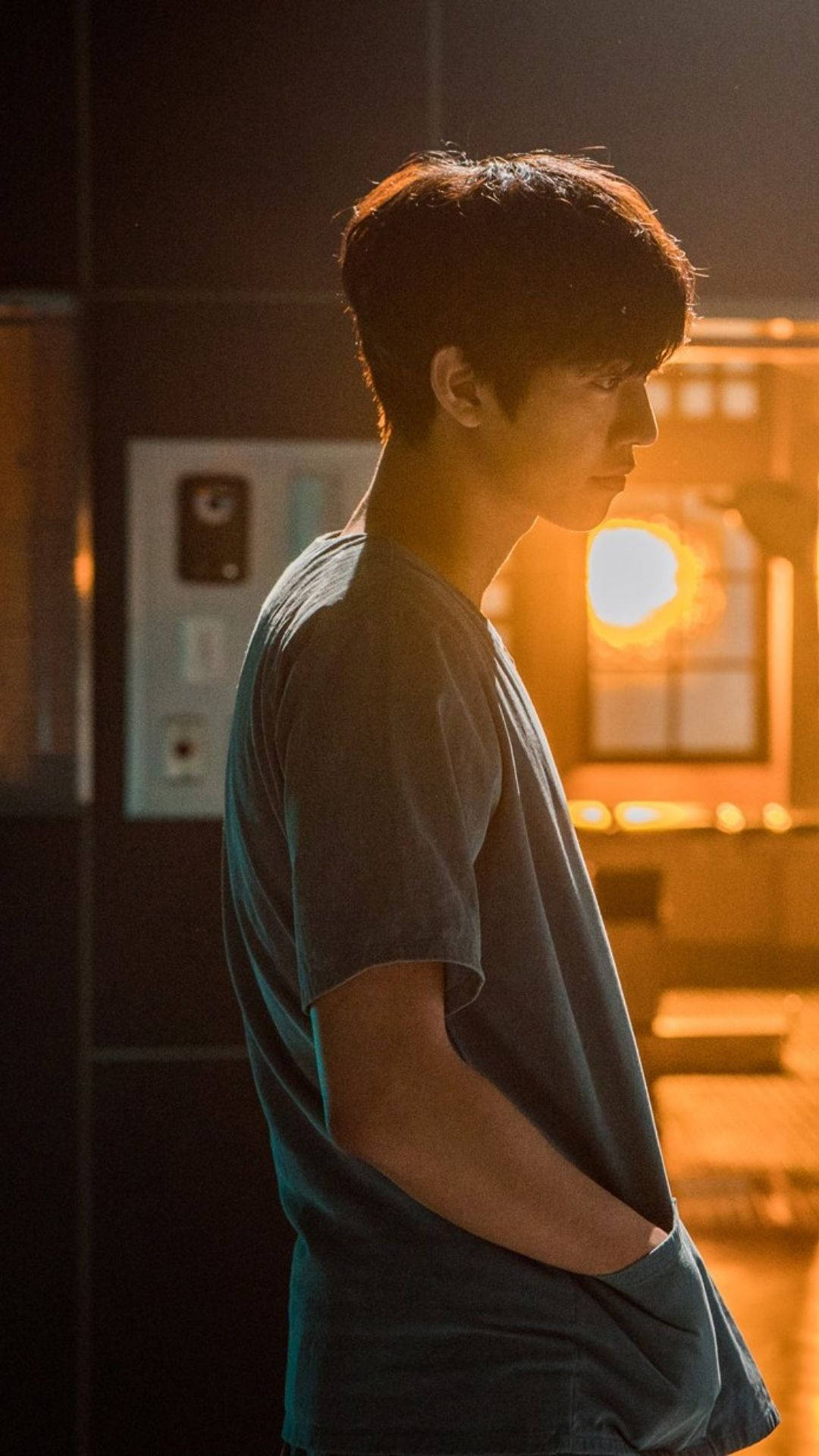 Ahn Hyo Seop 桌布 壁紙 — 一個穿著深色T恤的年輕男子側身站在溫暖照明的窗邊，帶有金色背光。