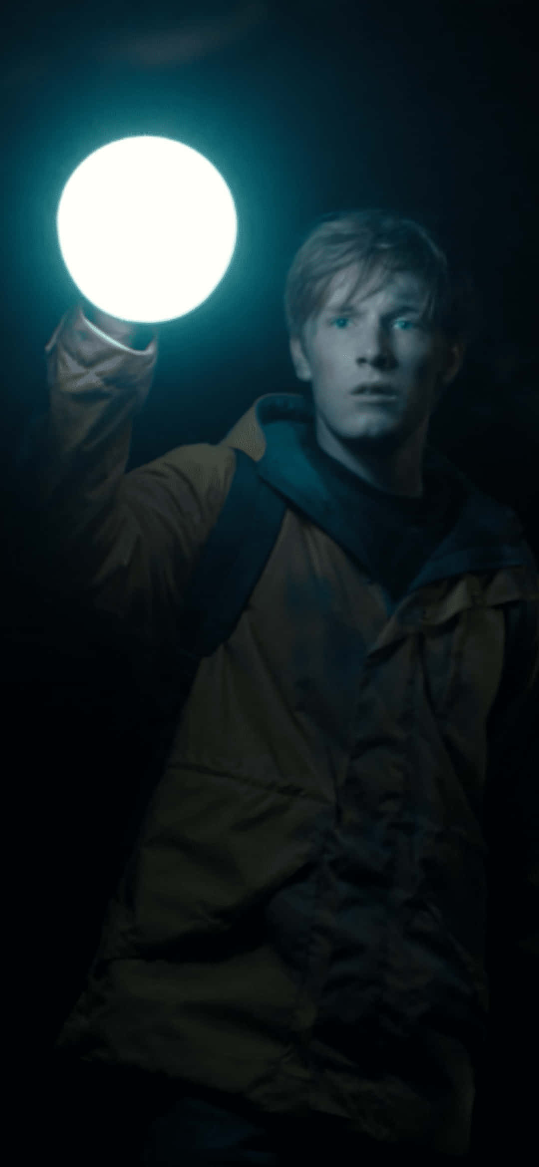 Dark Netflix 桌布 壁紙 — 一個穿著深色外套的年輕人在漆黑環境中手持發光球體，詭異的藍光照在他的臉上。
