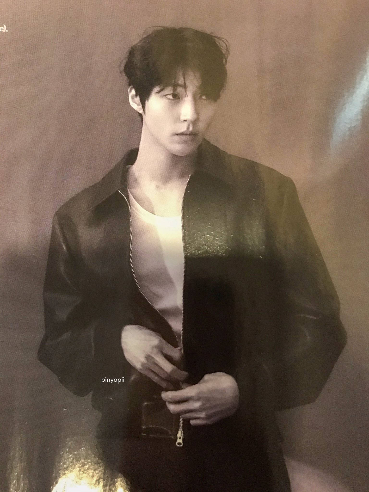 Hwang In Yeop 桌布 壁紙 — 一個穿著深色外套的年輕男子站在柔和的棕色牆前，柔和的光線凸顯他的臉和手。