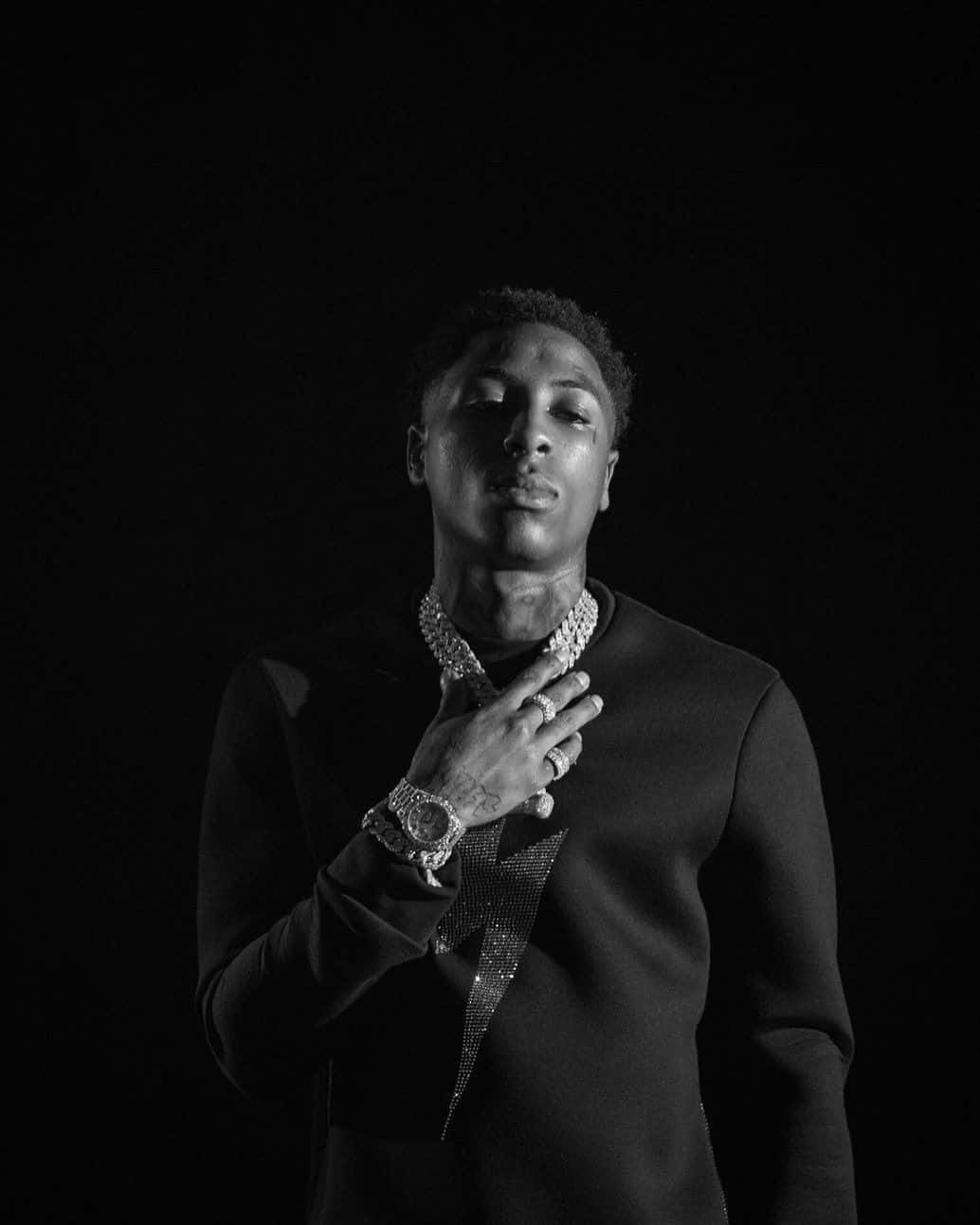 Youngboy 桌布 壁紙 — 一個穿著深色毛衣、飾有閃亮珠寶的男子在純黑色背景下的黑白肖像。