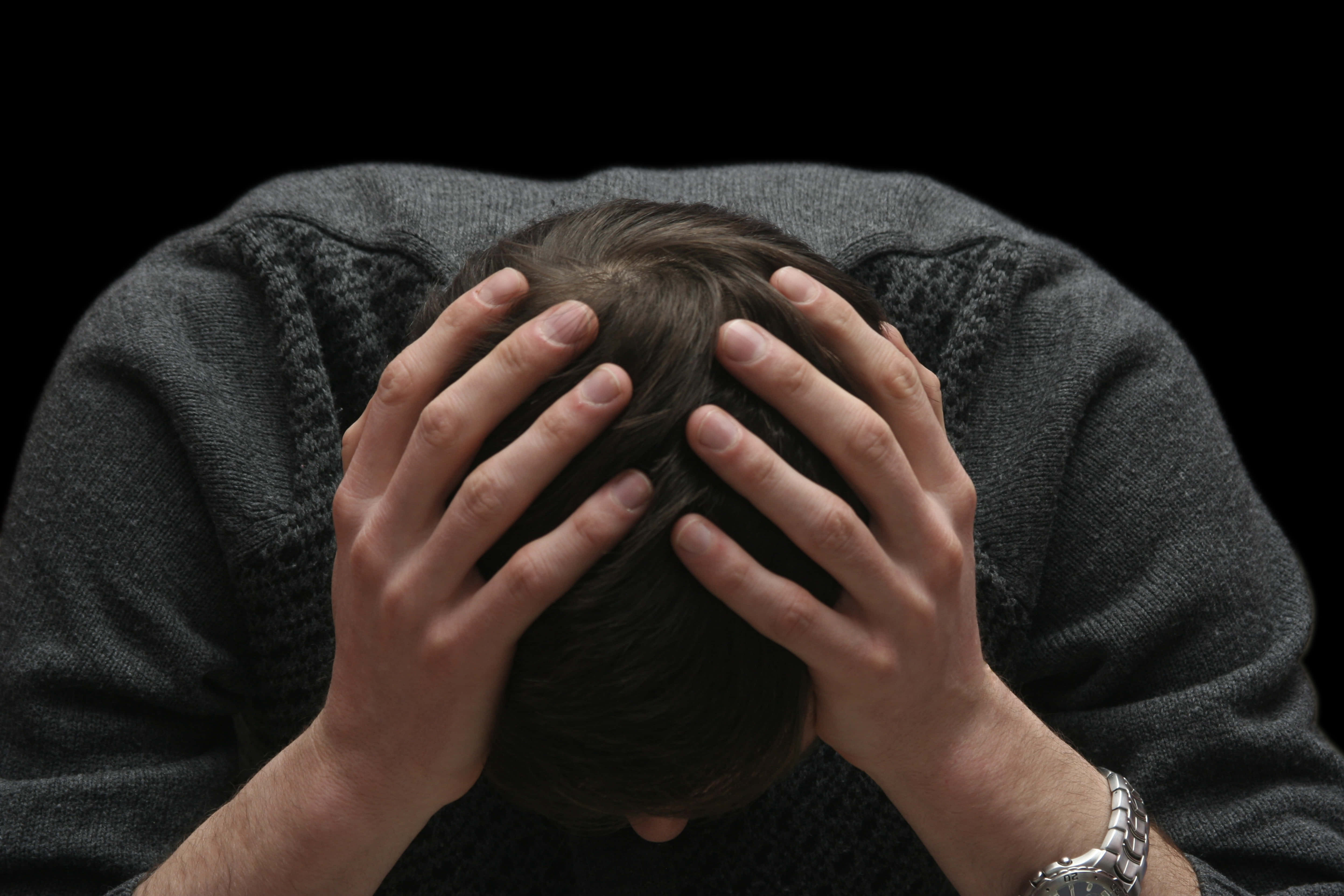 grief 桌布 壁紙 — 一個穿著深色毛衣的人，在黑色背景前將頭埋進雙手。