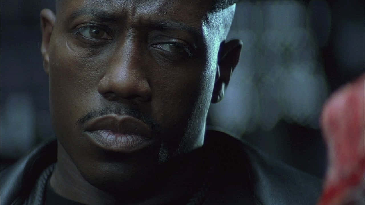Wesley Snipes 桌布 壁紙 — 一個穿著深色皮夾克、表情嚴肅的男人在昏暗藍色燈光下的特寫。