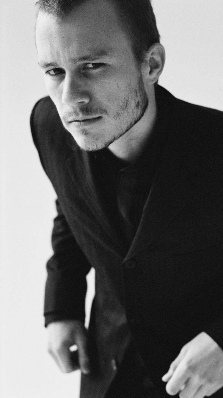 Heath Ledger 桌布 壁紙 — 一個穿著深色西裝的男人在純色背景下凝視鏡頭的黑白肖像。