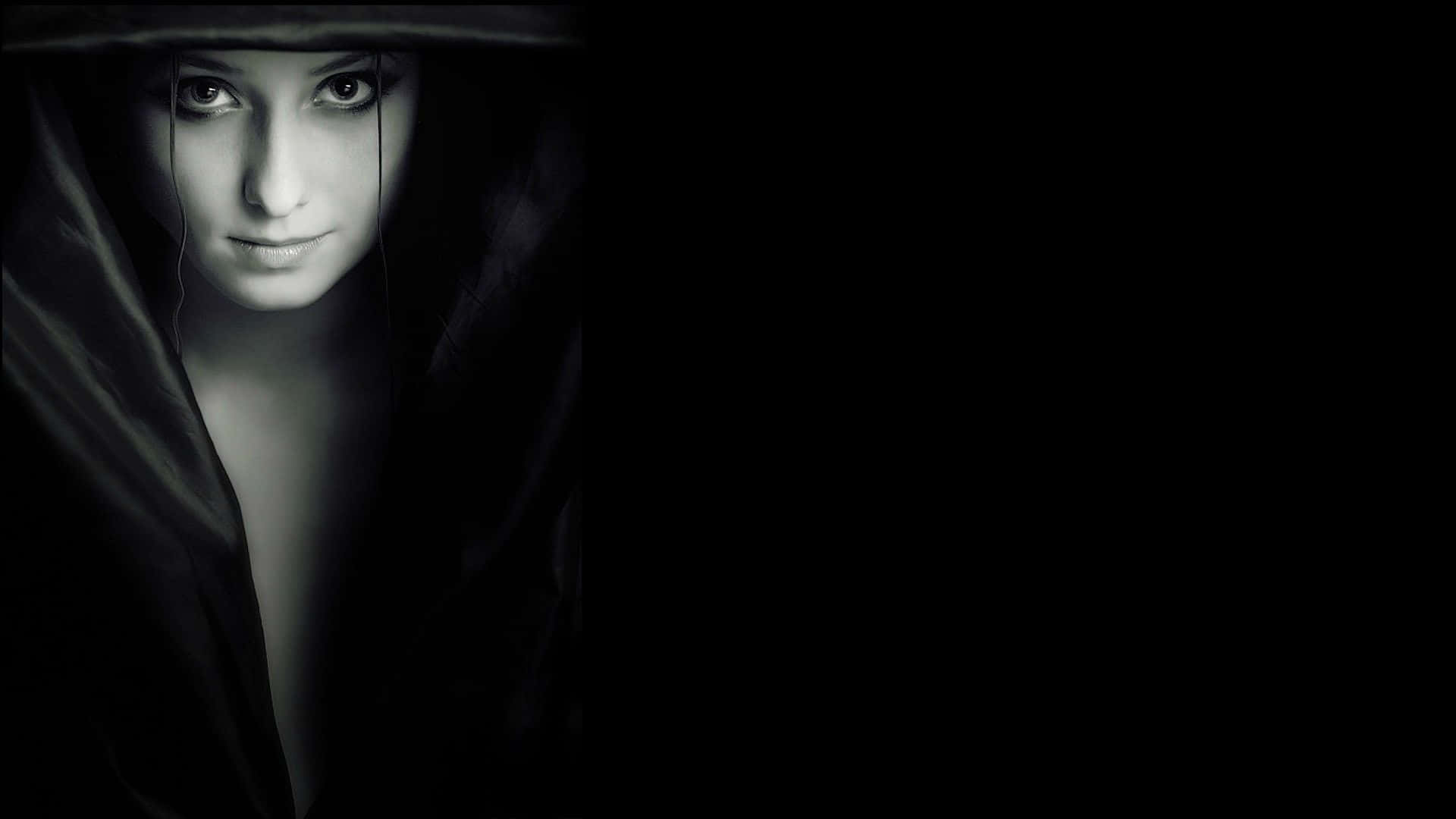 Black Is Beautiful 桌布 壁紙 — 一個穿著深色連帽斗篷的女人從陰影黑暗中用令人難忘的明亮眼睛專注地凝視。