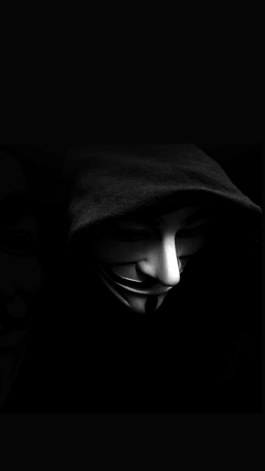 Mask 桌布 壁紙 — 一個穿著深色連帽衫的人，在戲劇性的低調燈光下戴著白色蓋伊·福克斯面具。